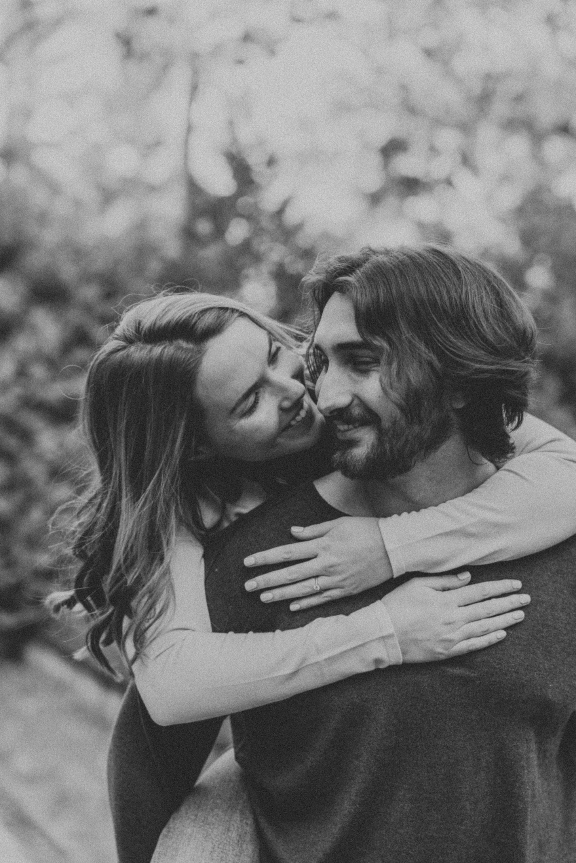 A candid black-and-white shot of an engaged couple embracing, capturing a tender and intimate moment during their engagement session.