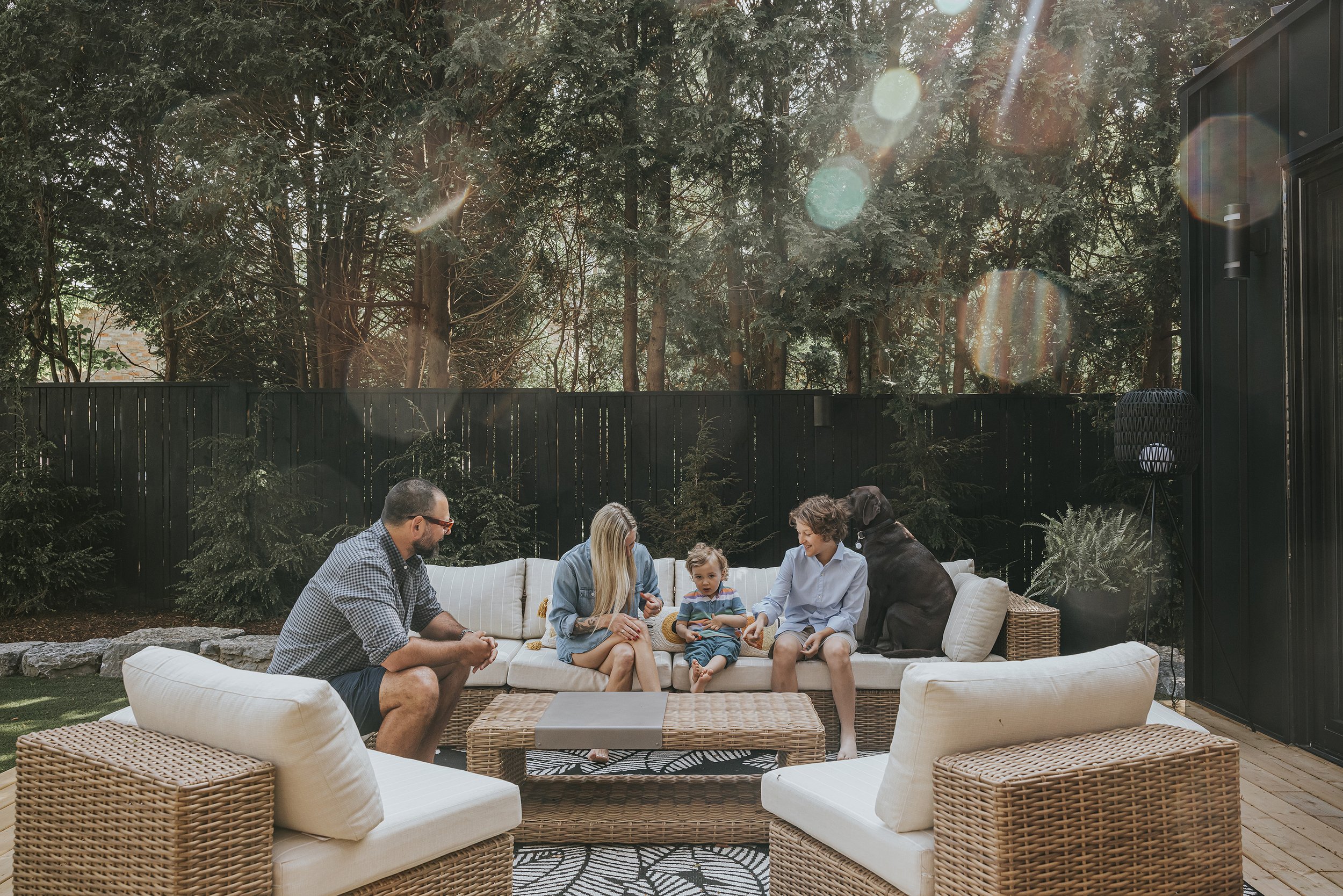A family enjoying a sunny day together outdoors, with sunlight streaming through the trees.