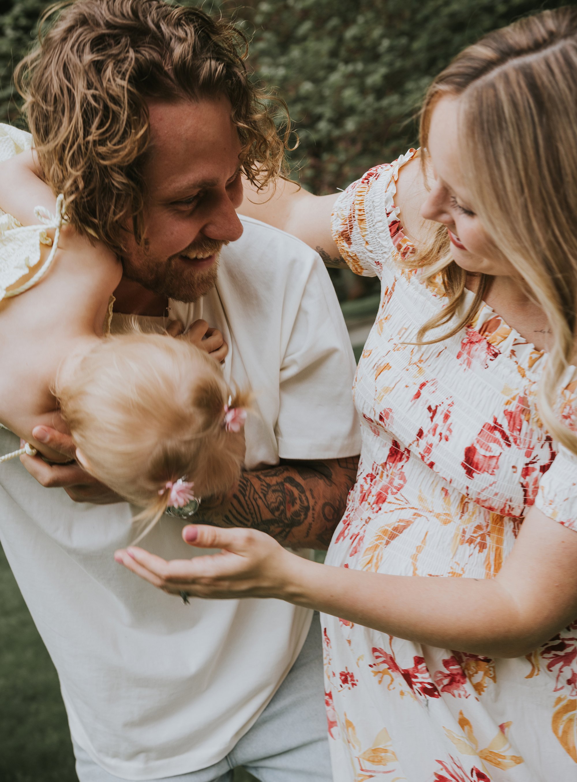 A joyful family moment captured as parents laugh and play with their young child, creating a lively and warm atmosphere.