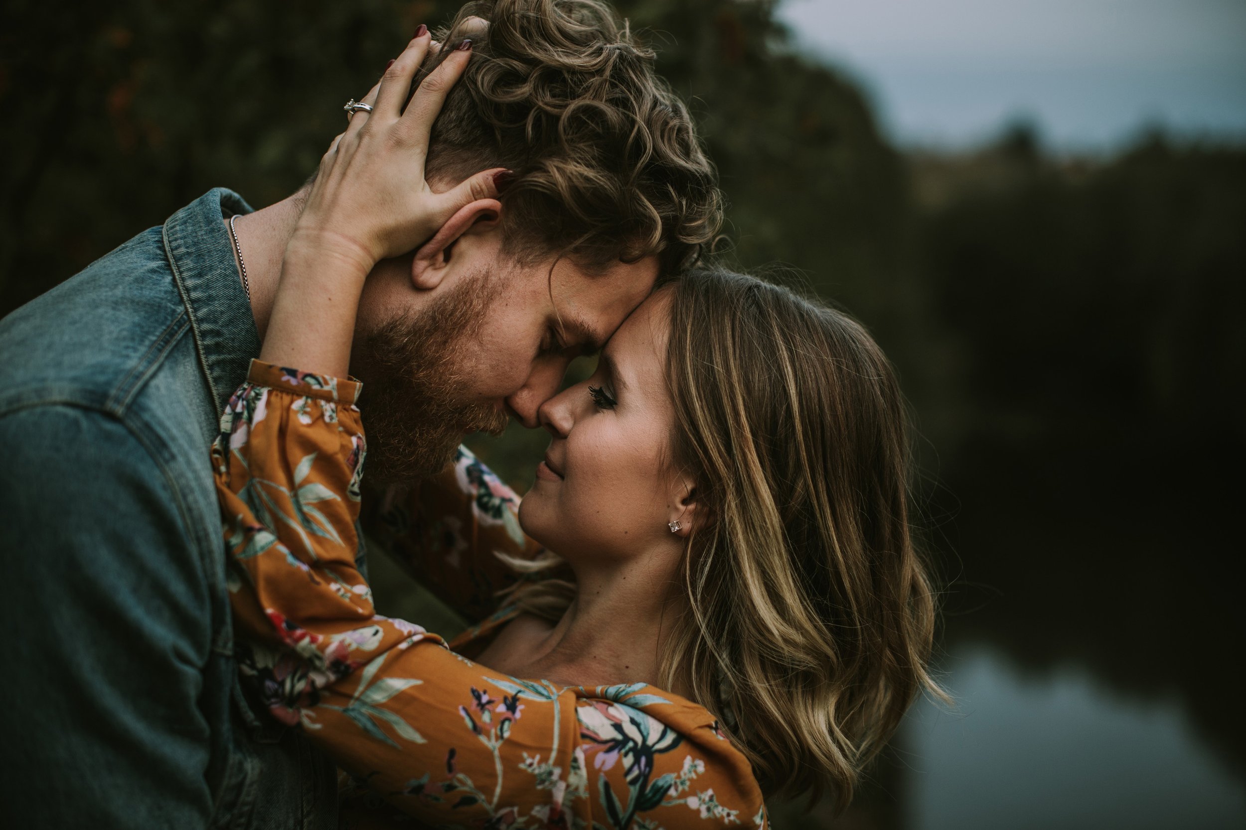 A couple shares an intimate forehead kiss during their engagement session.