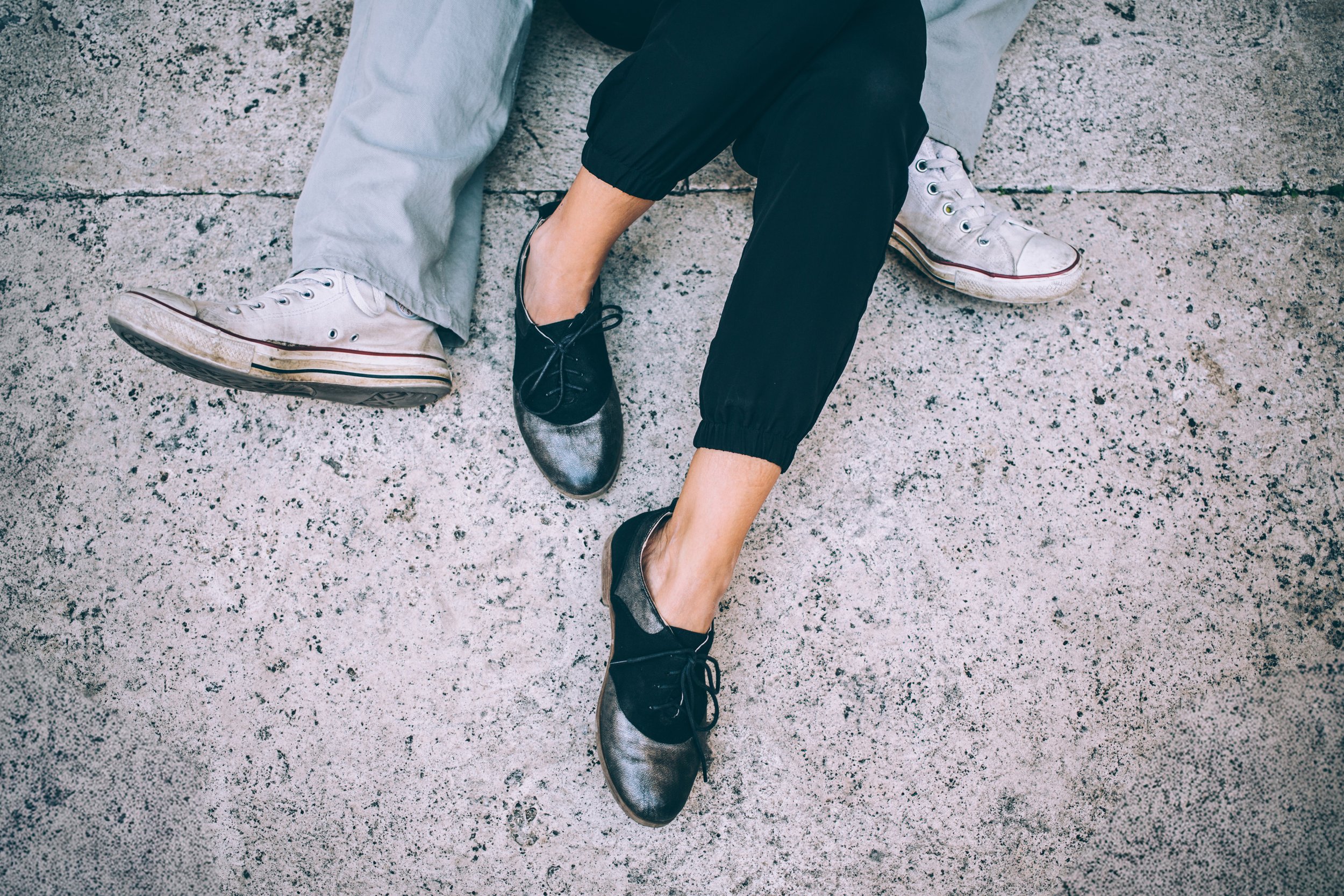 A close-up of a couple's feet resting together on the ground, symbolizing a relaxed and connected moment.