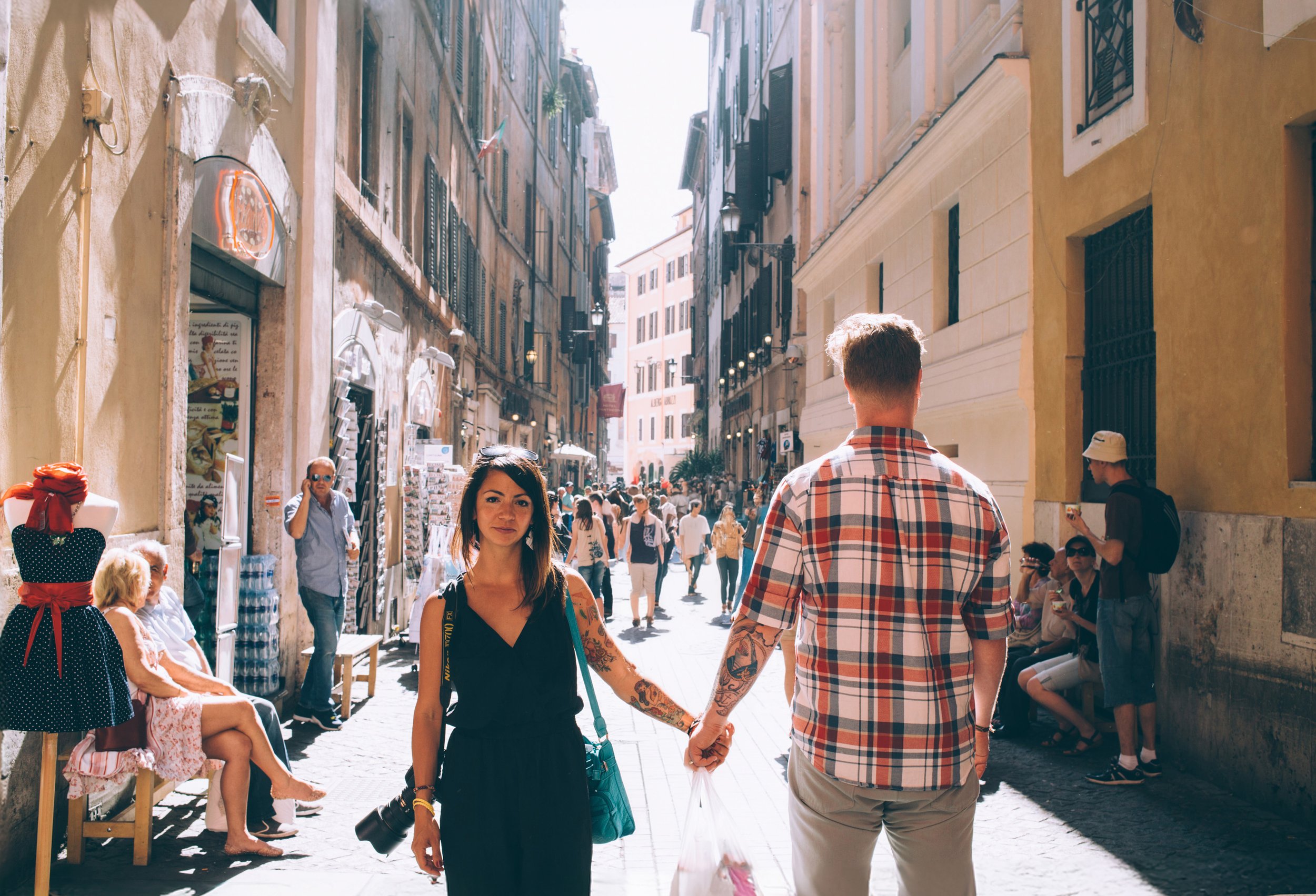 Couple walking hand-in-hand down a bustling Italian street, capturing the essence of a romantic adventure.