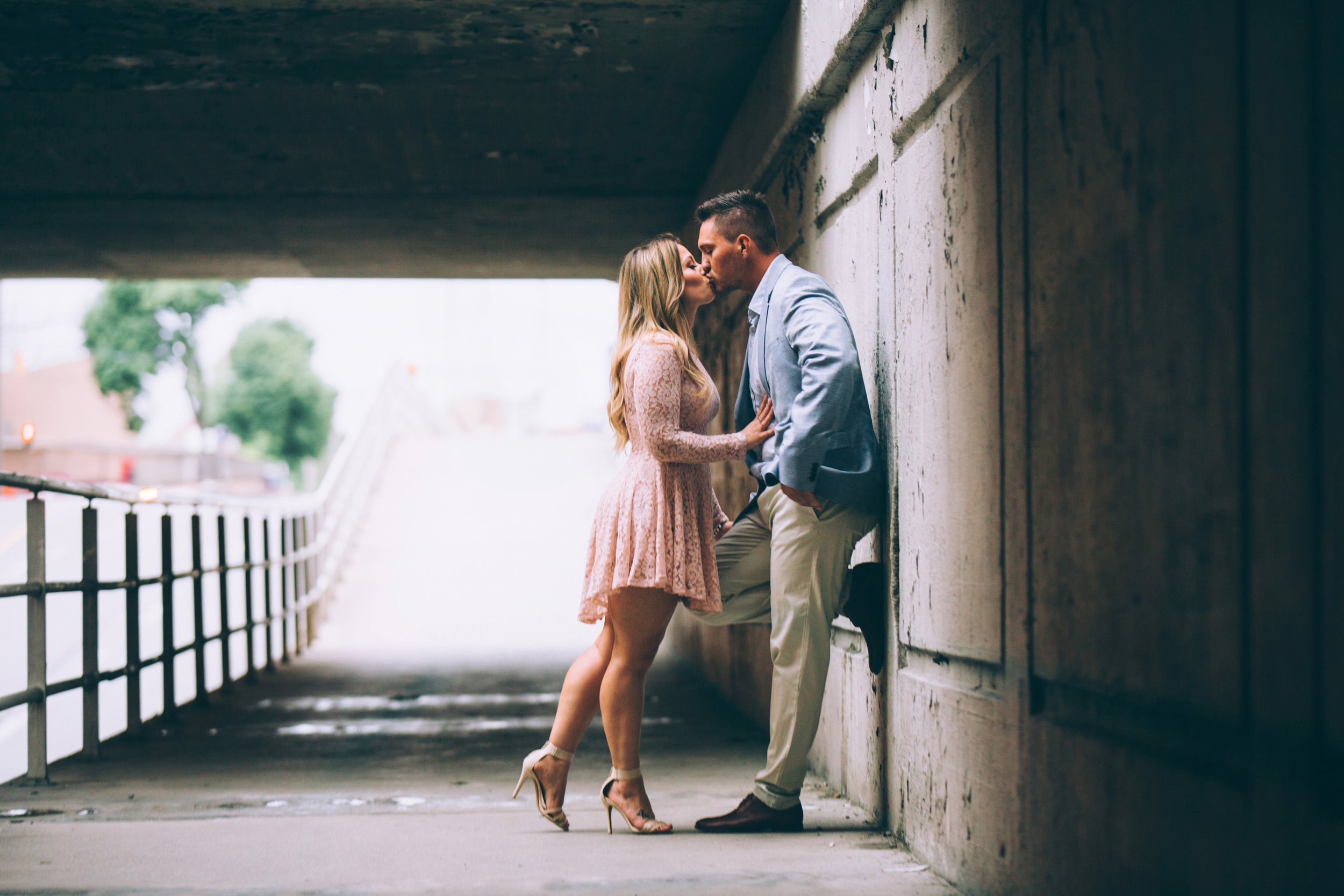 A couple kissing under an urban underpass, captured in a tender and intimate moment.