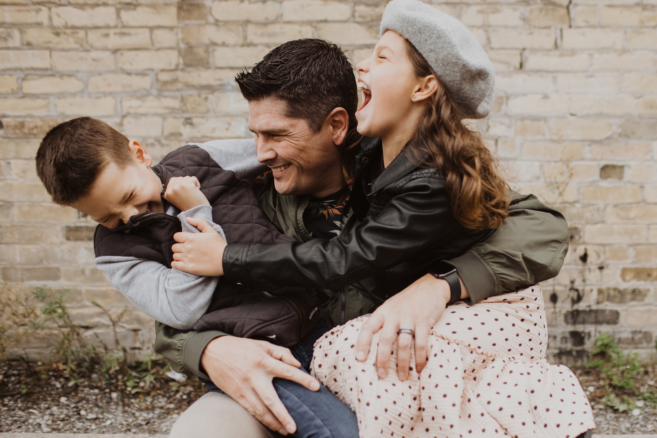 A father laughing and hugging his two children, captured in a joyful and candid moment of family love and connection.