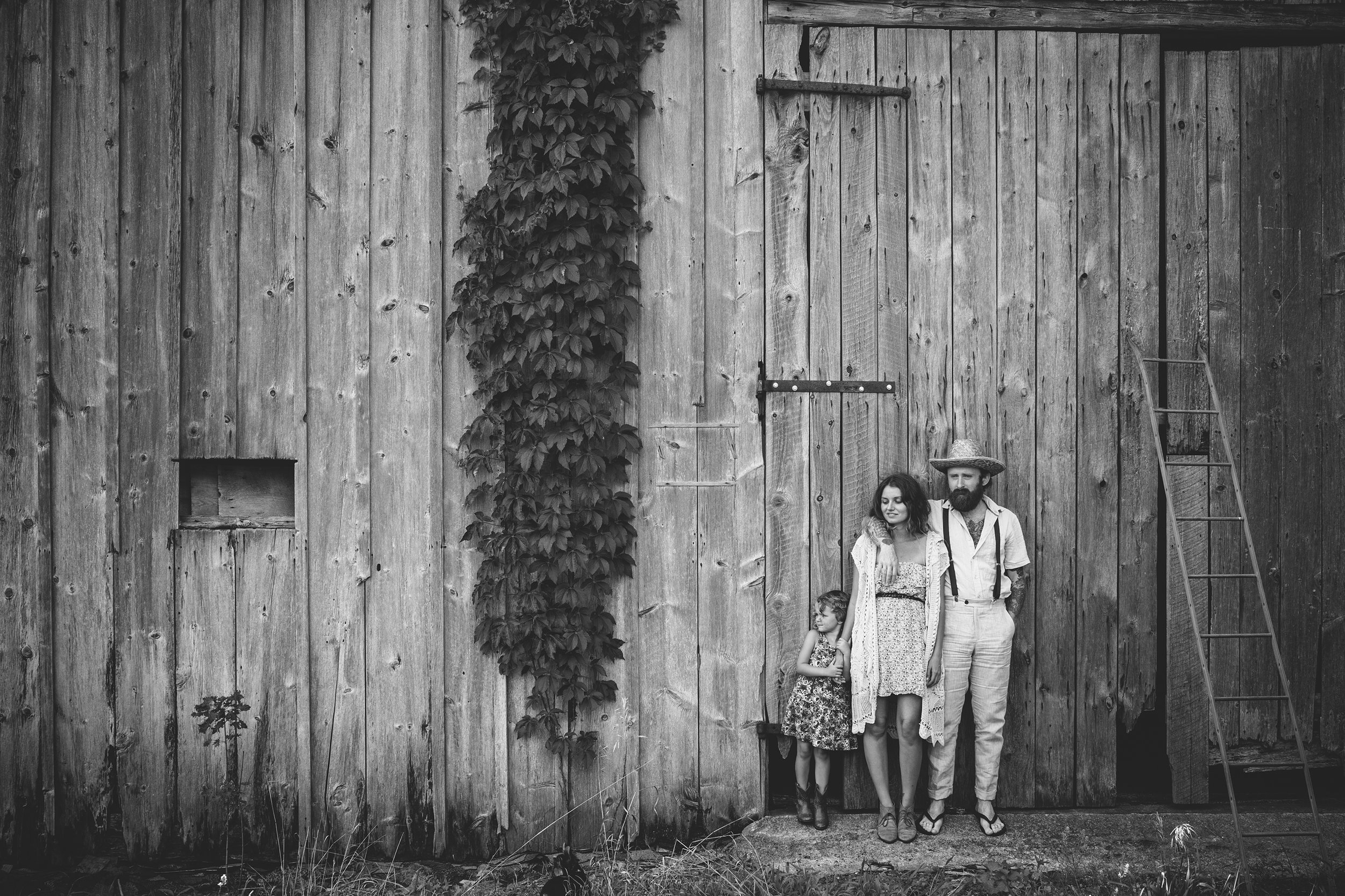 A vintage family portrait taken in front of a rustic barn, emphasizing a timeless, rural aesthetic.