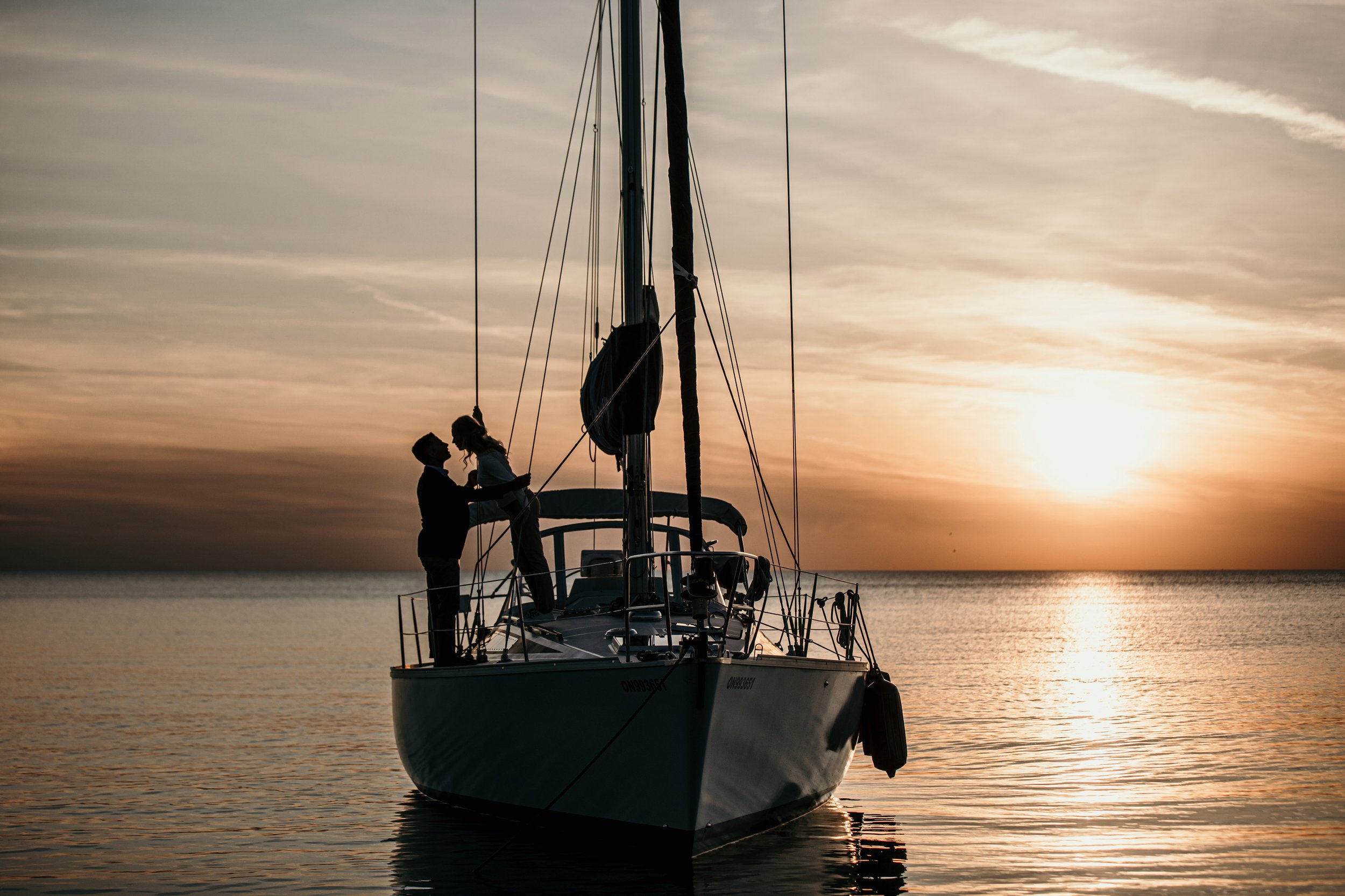 A couple shares a kiss on a yacht during a breathtaking sunset, epitomizing luxury and romance.