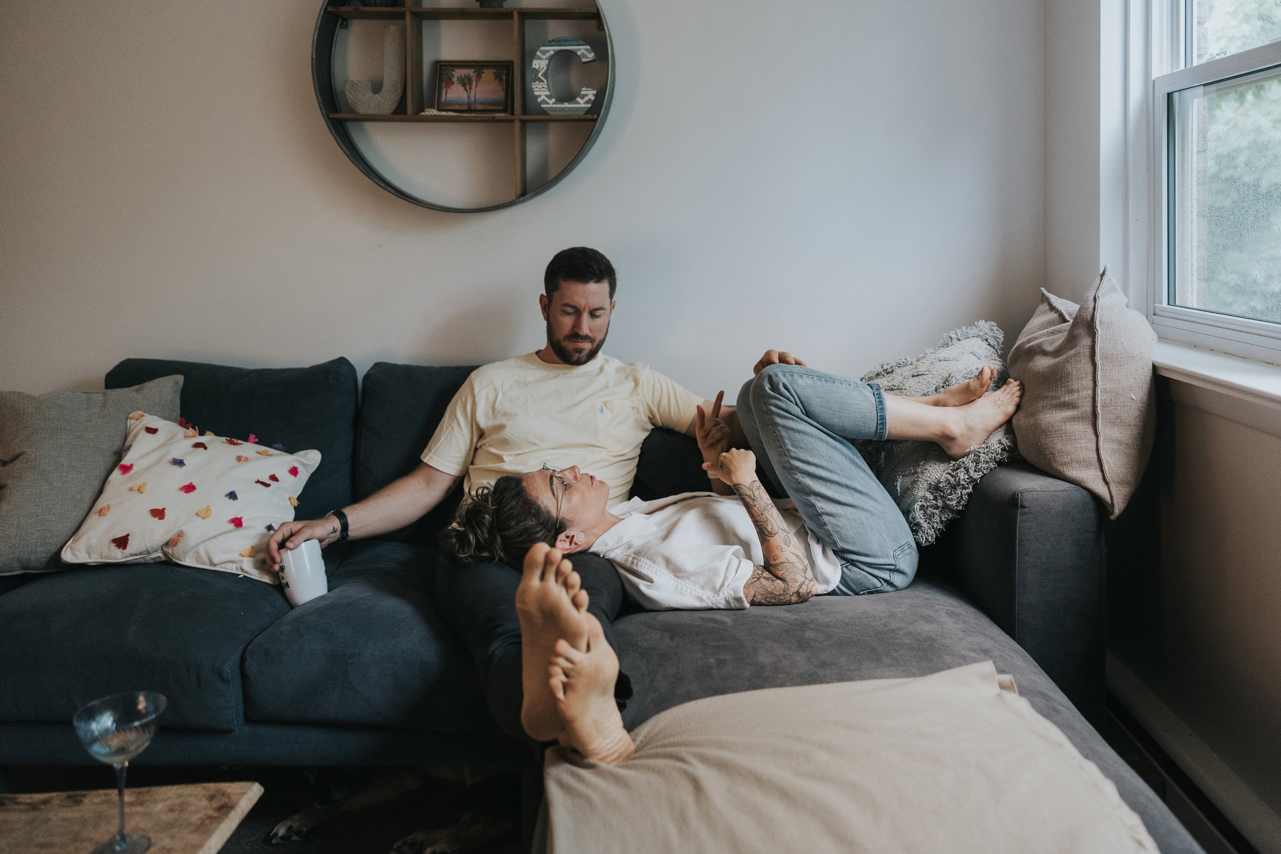 A couple lounges on a comfortable couch in their cozy home, sharing a quiet, intimate moment together.