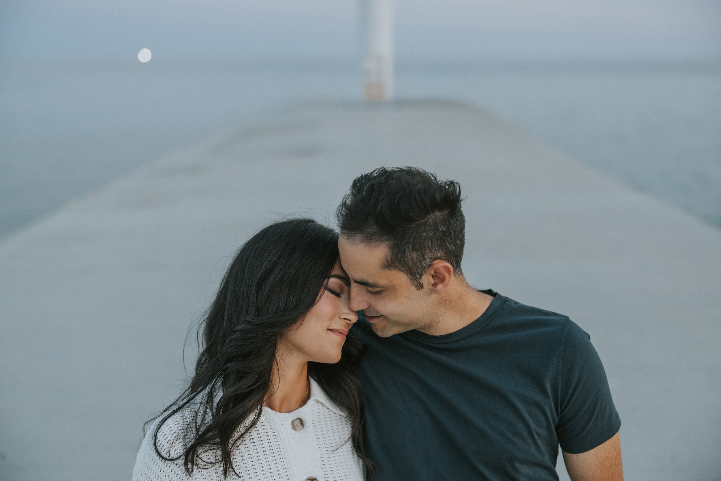 A couple embraces lovingly on a beach at sunset, the warm golden light highlighting their closeness as they share a tender moment by the ocean.
