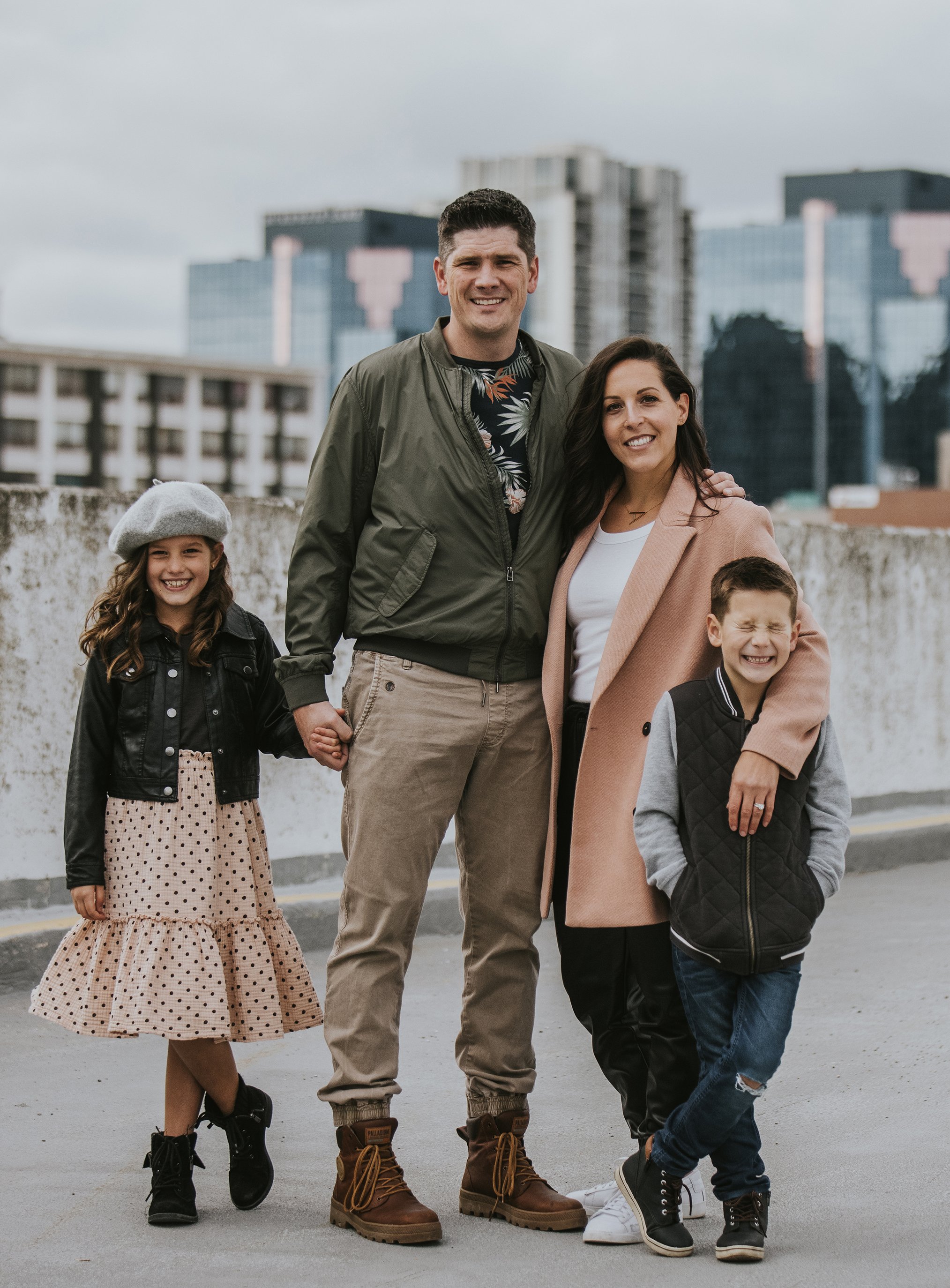 An urban family portrait taken during a rooftop session in London, Ontario, with city buildings in the background.