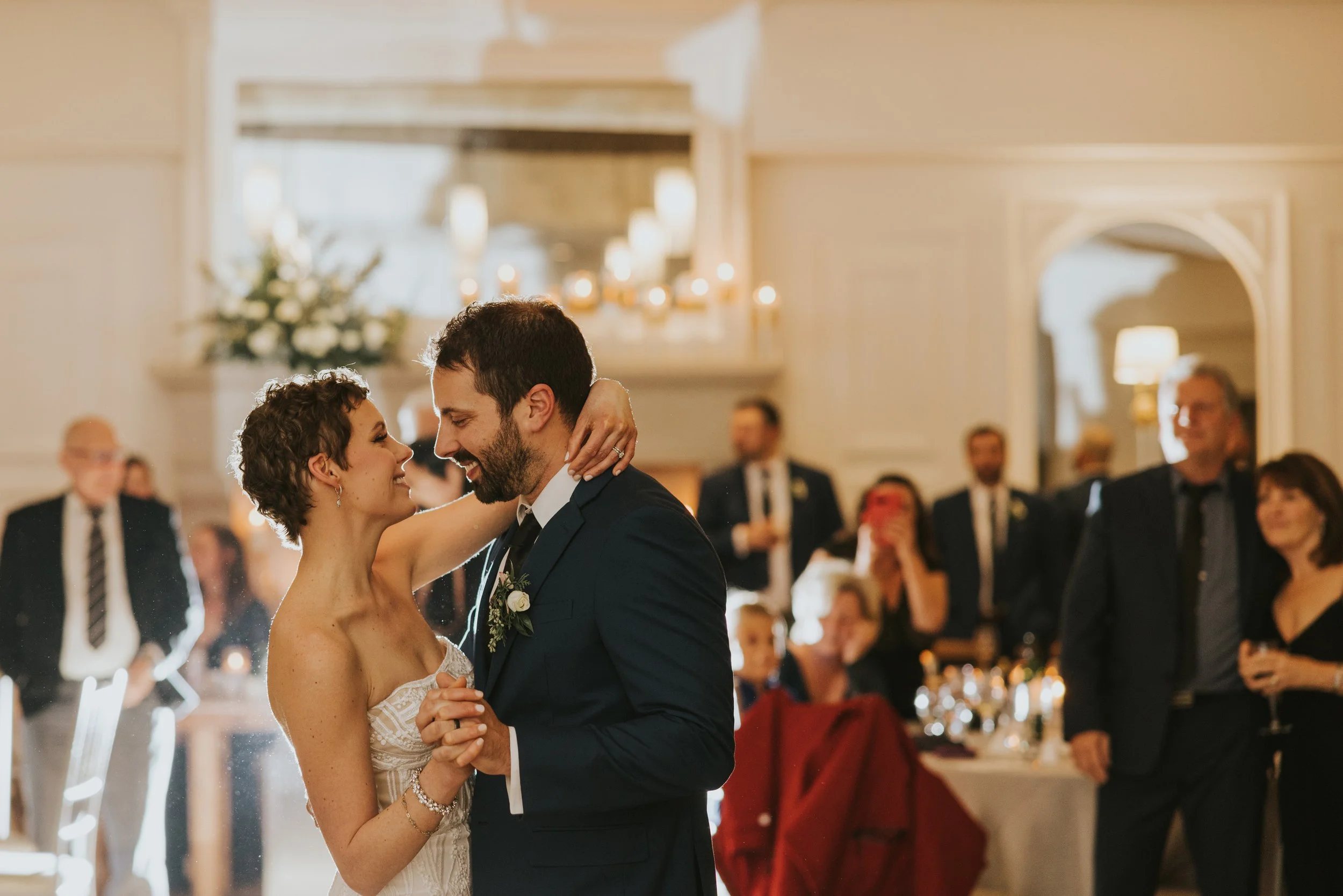 Close-up of bride and groom holding hands, showcasing the bride’s elegant lace wedding dress.