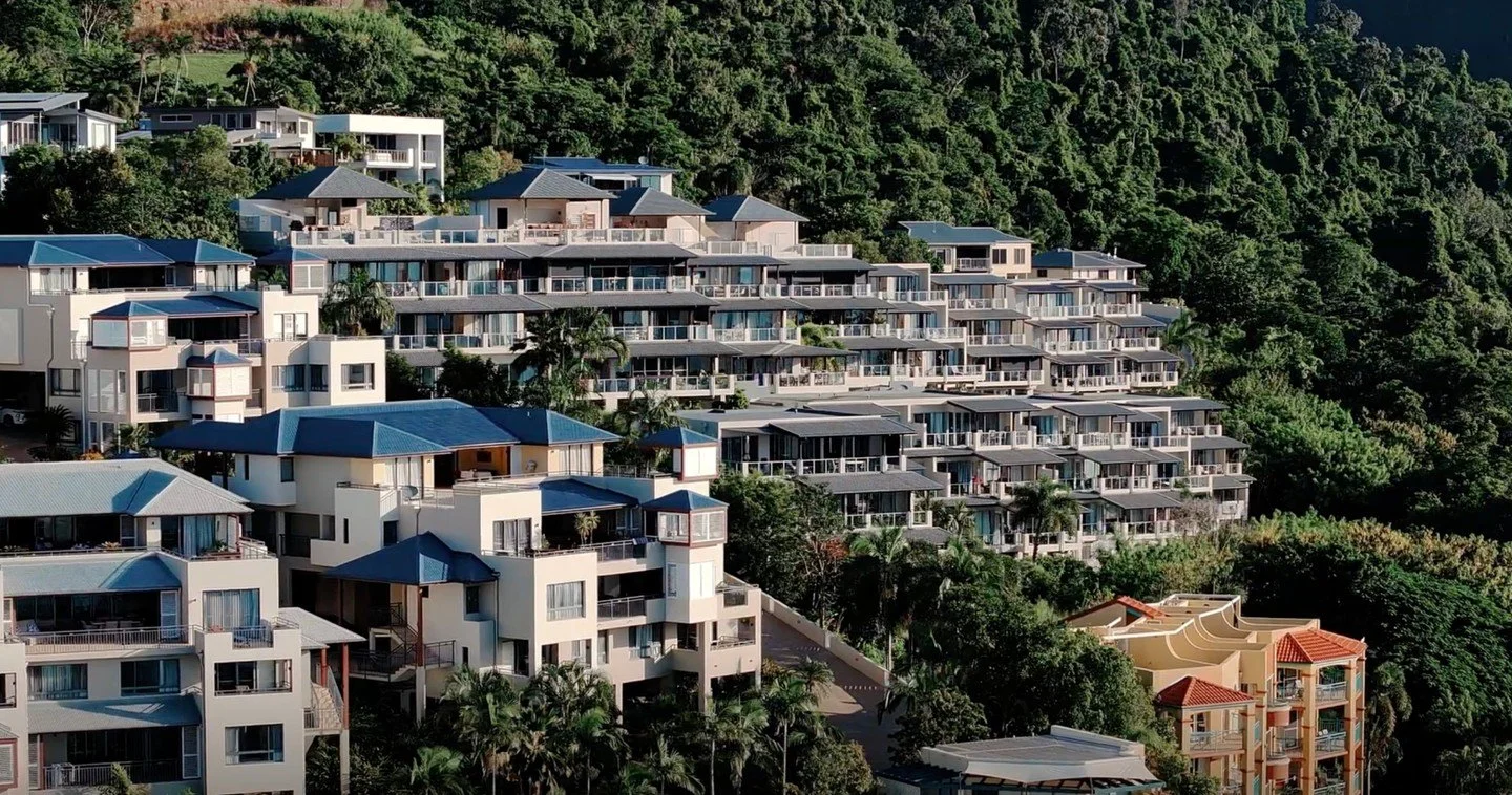 Most coastal towns expand outwards.

Airlie Beach had no choice but to build upwards.

Nestled between the Coral Sea and rainforest-covered mountains, the landscape has shaped a town unlike anywhere else in Australia. Homes cling to the hillsides, ap