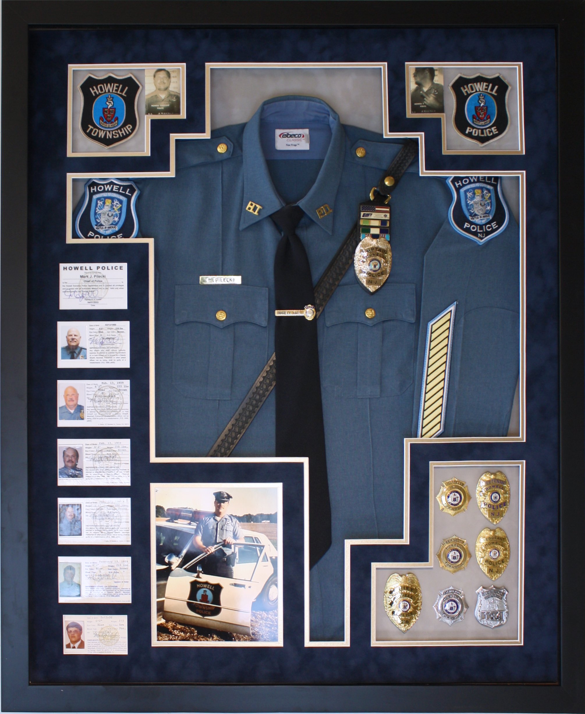Framed police memorabilia display featuring a police uniform, badges, photographs, and documents from Howell Police Department. Custom framed in a shadowbox display.