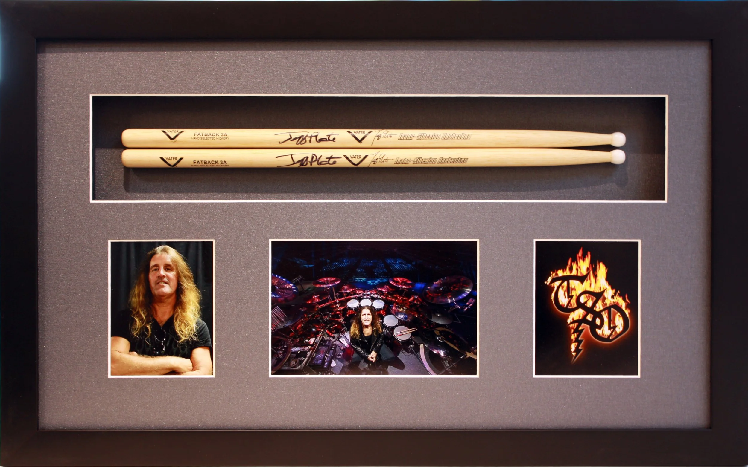 Display case with two drumsticks, a photograph of a man with long hair, a photo of a drum set, and a flaming logo with the initials T B D. Custom framed in a shadowbox display.