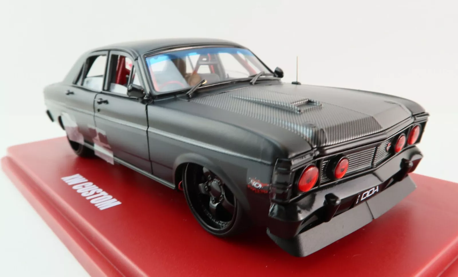 Limited-edition 1:24 scale DDA Ford Falcon XW 1969 “Inferno” die-cast model – matte black, carbon-look bonnet, red headlights, window-box packaging.