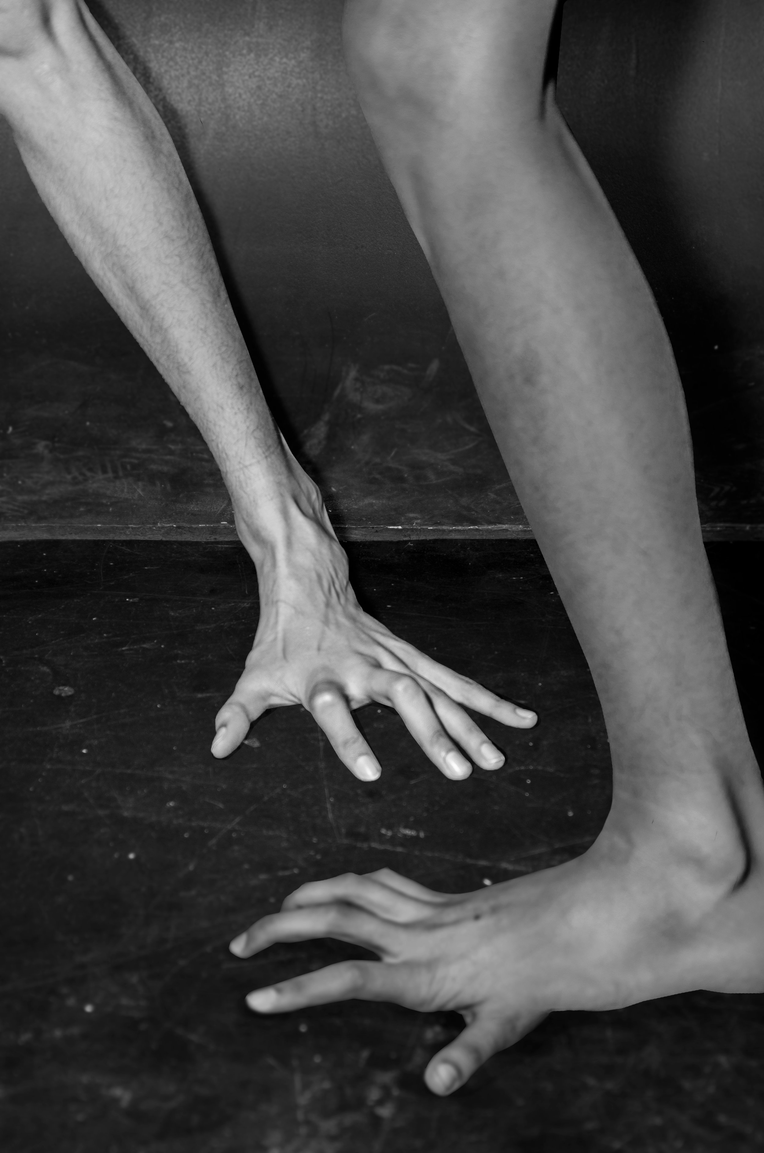 Black and white photo of two hands reaching towards each other on a dark surface.
