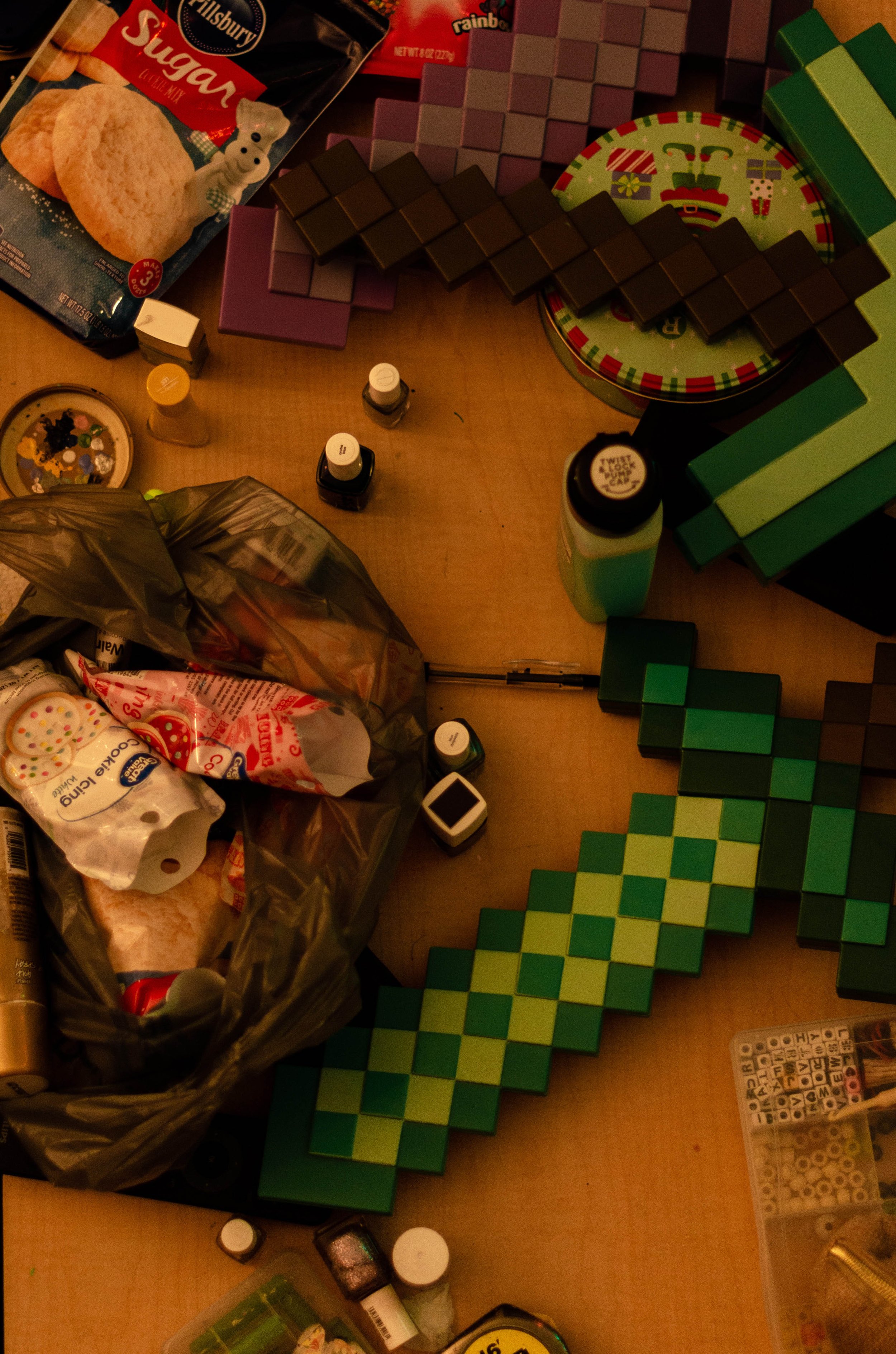 A cluttered table with colorful building blocks, toy candies, bottles of paint, and craft supplies.