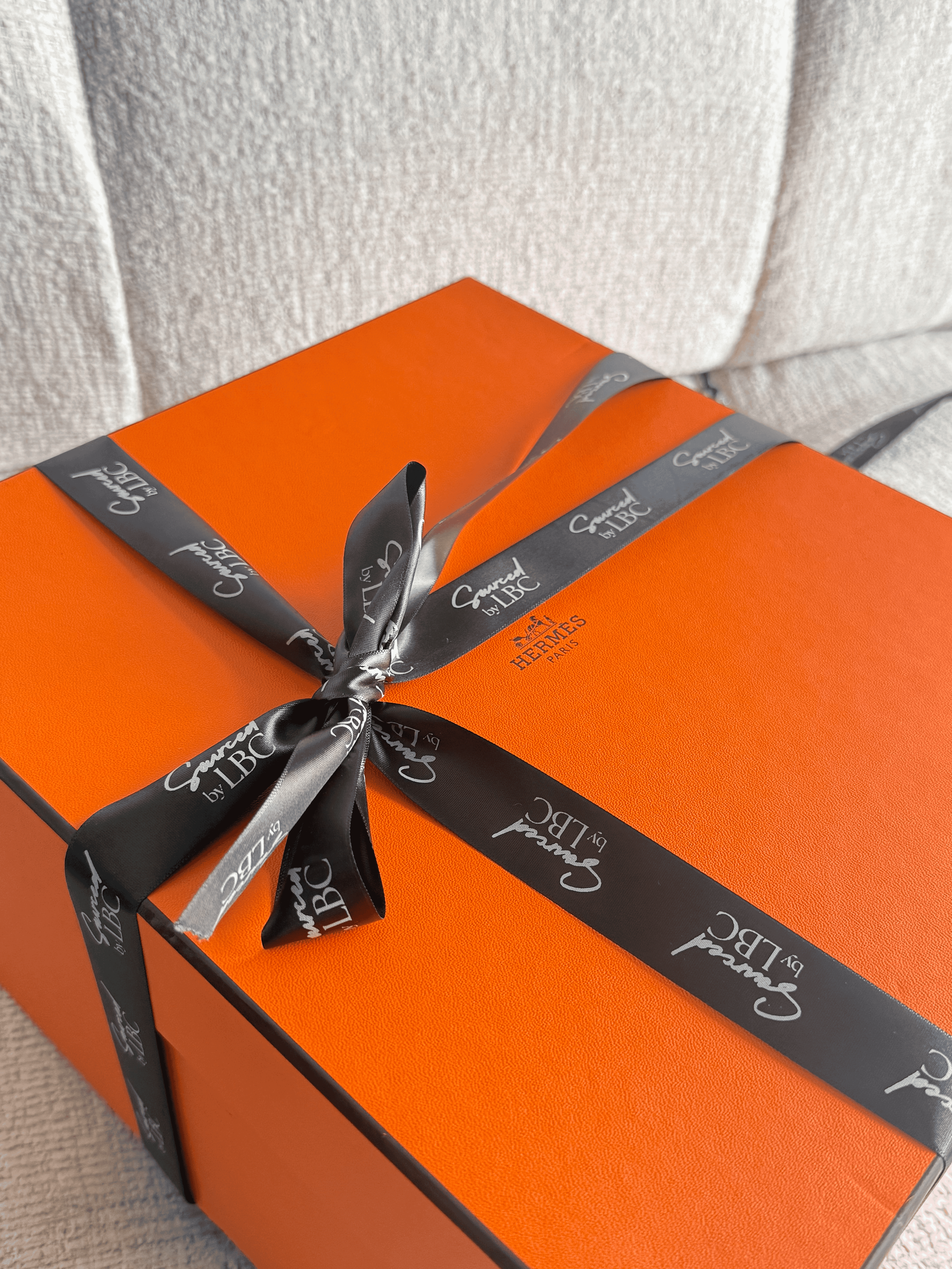 Orange Hermès box with black ribbon branded Sourced by LBC