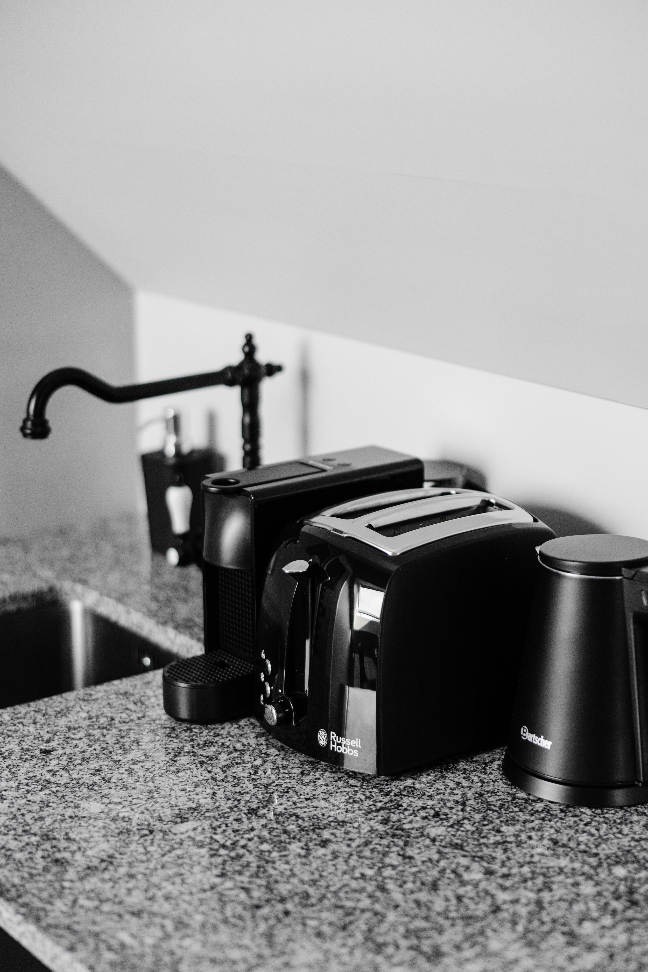 Black and silver toaster on a speckled granite kitchen counter with a coffee maker nearby.