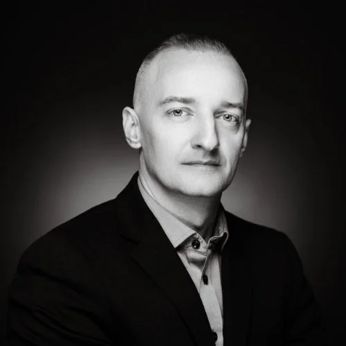 Black and white portrait of a man with short hair, wearing a suit jacket and collared shirt.