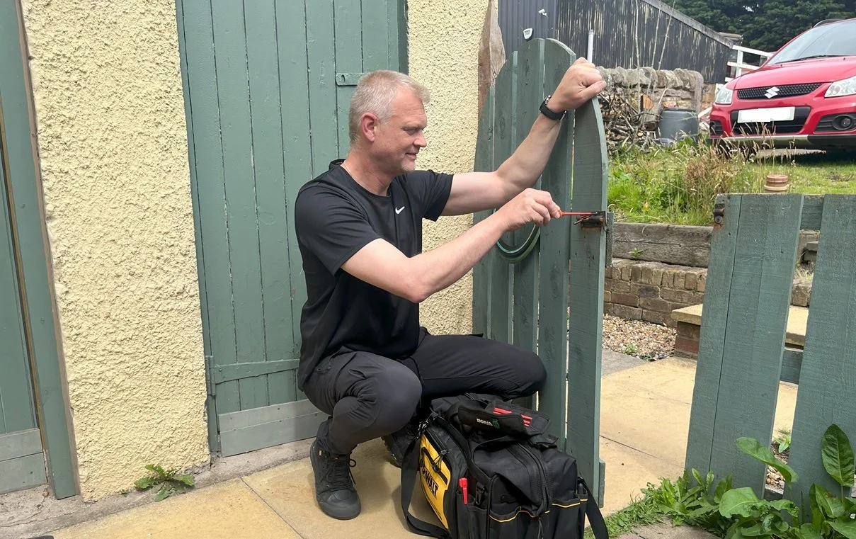 Frank from So Handyman Edinburgh repairing and installing a secure lock on a timber garden gate.