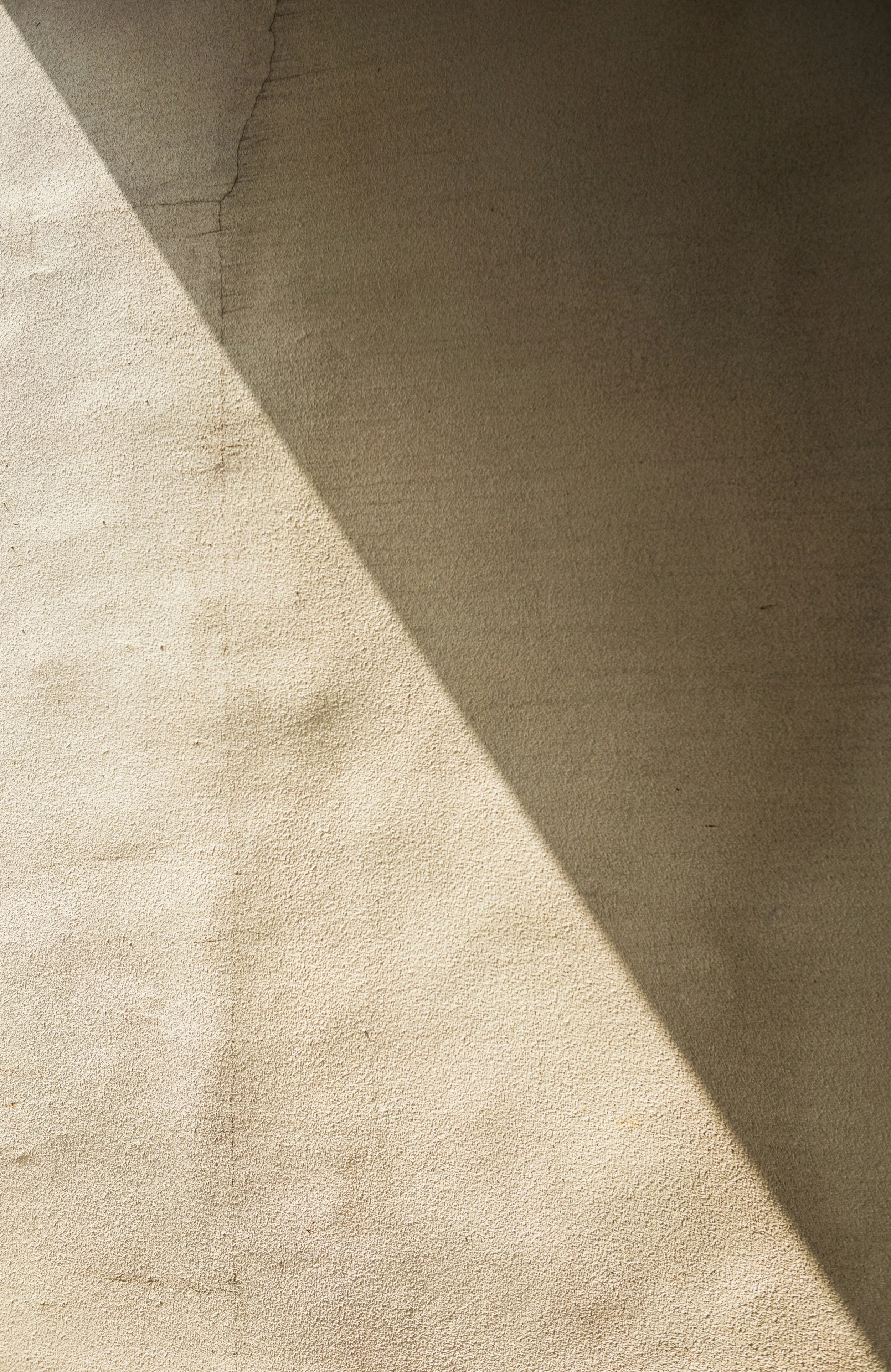 Close-up photo of a wall with a diagonal shadow dividing the light and dark stone surfaces.
