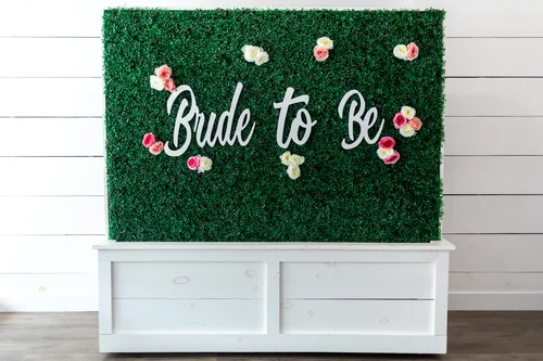 'Bride to Be' sign with roses and florals on the greenery wall