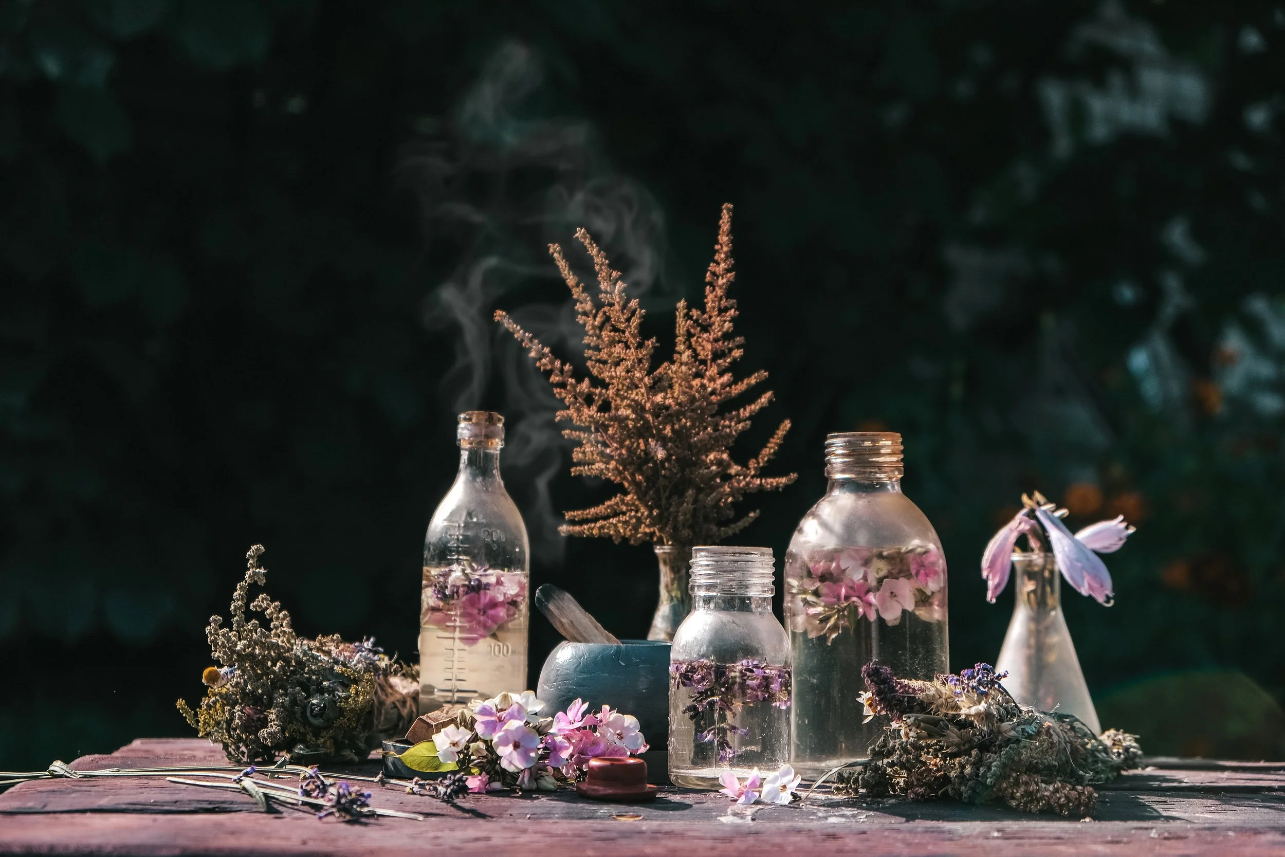 Flower essence vials and dried botanicals arranged outdoors at Wild Thistle Herbs and Alchemy