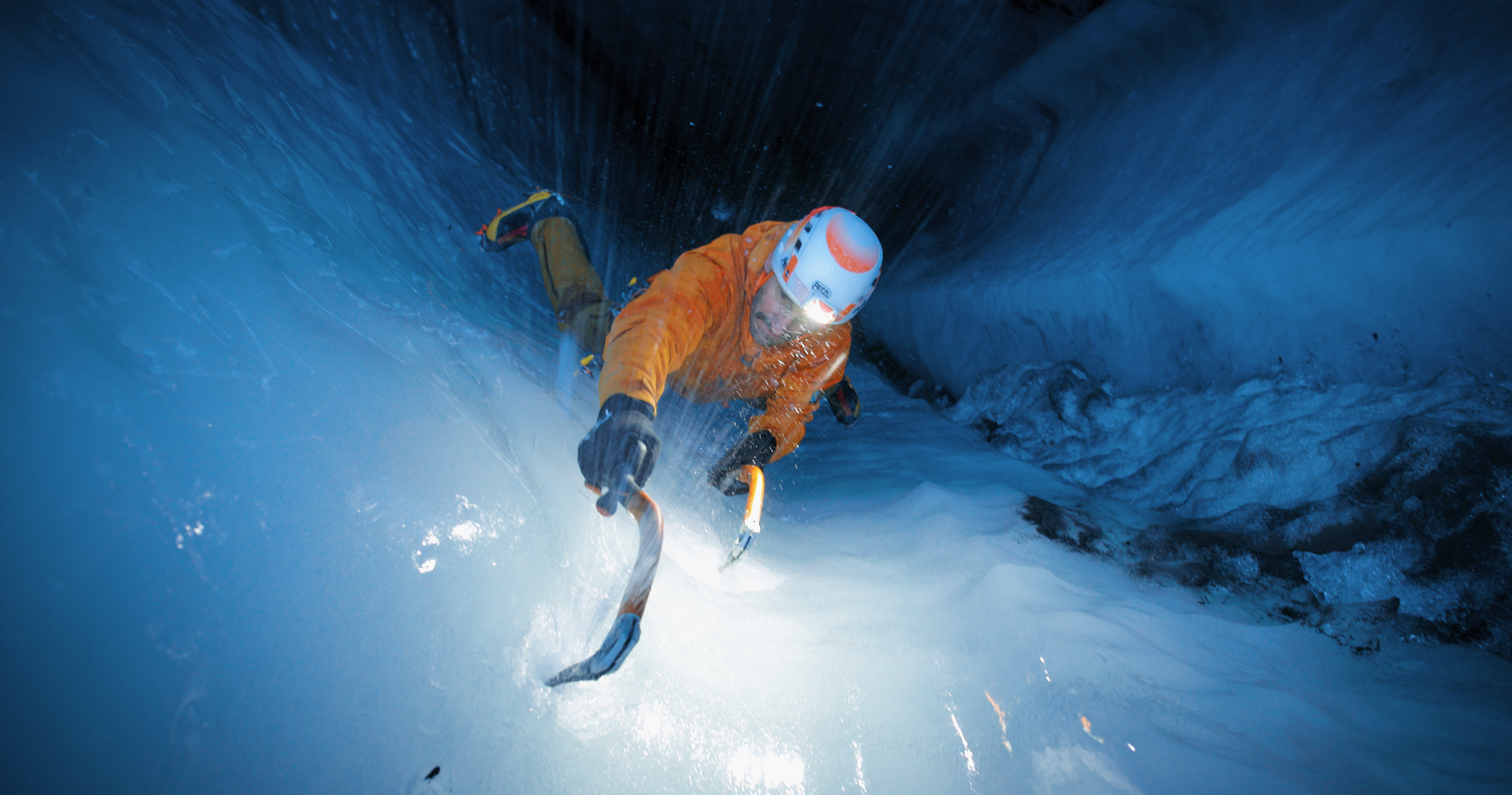 Ice climber hitting the ice wearing Petzl helmet and Rab gear