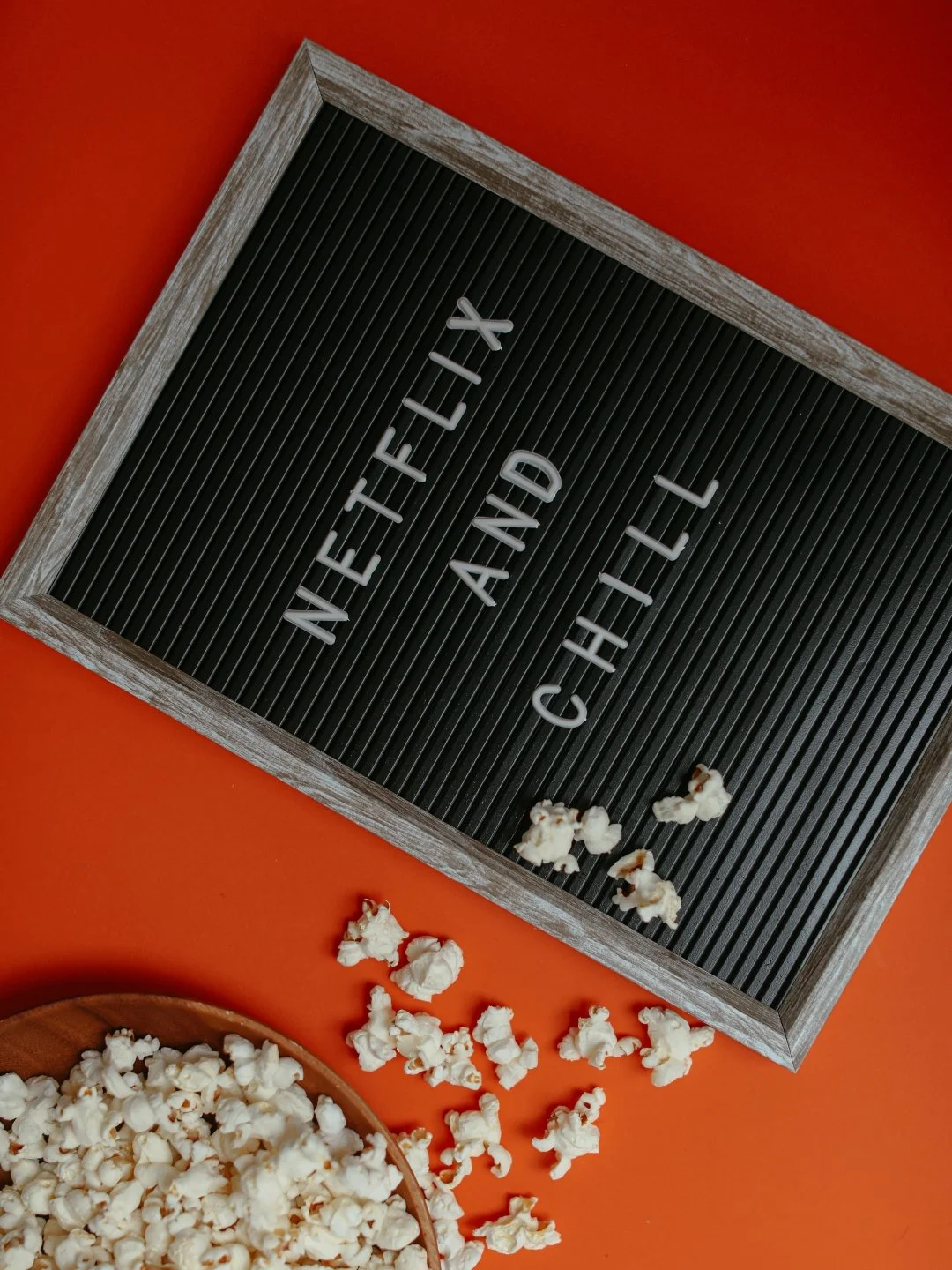 board with text "Netflix and chill" near a bucket of popocorns