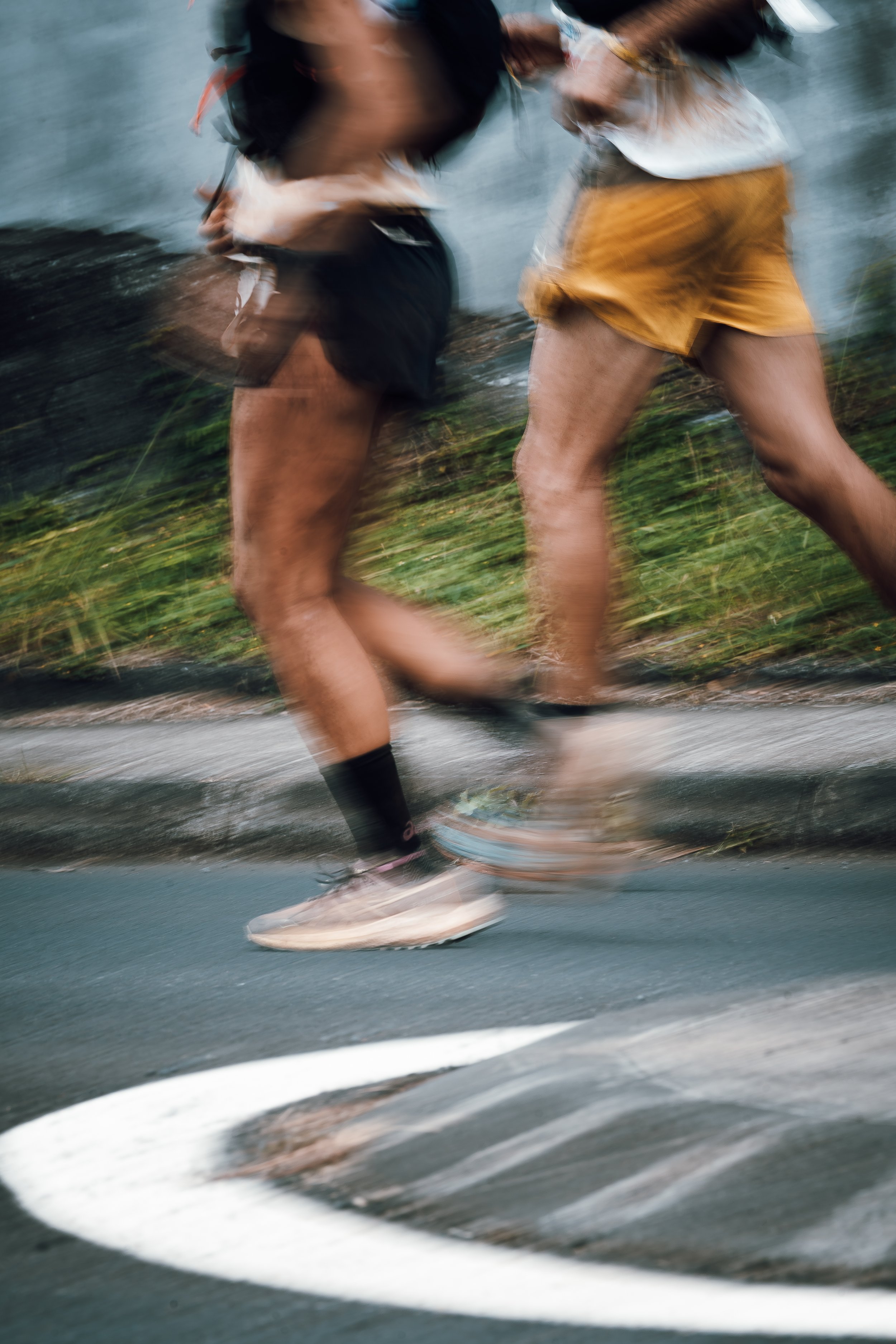 Blurry image of two trail runners wearing Asics clothes
