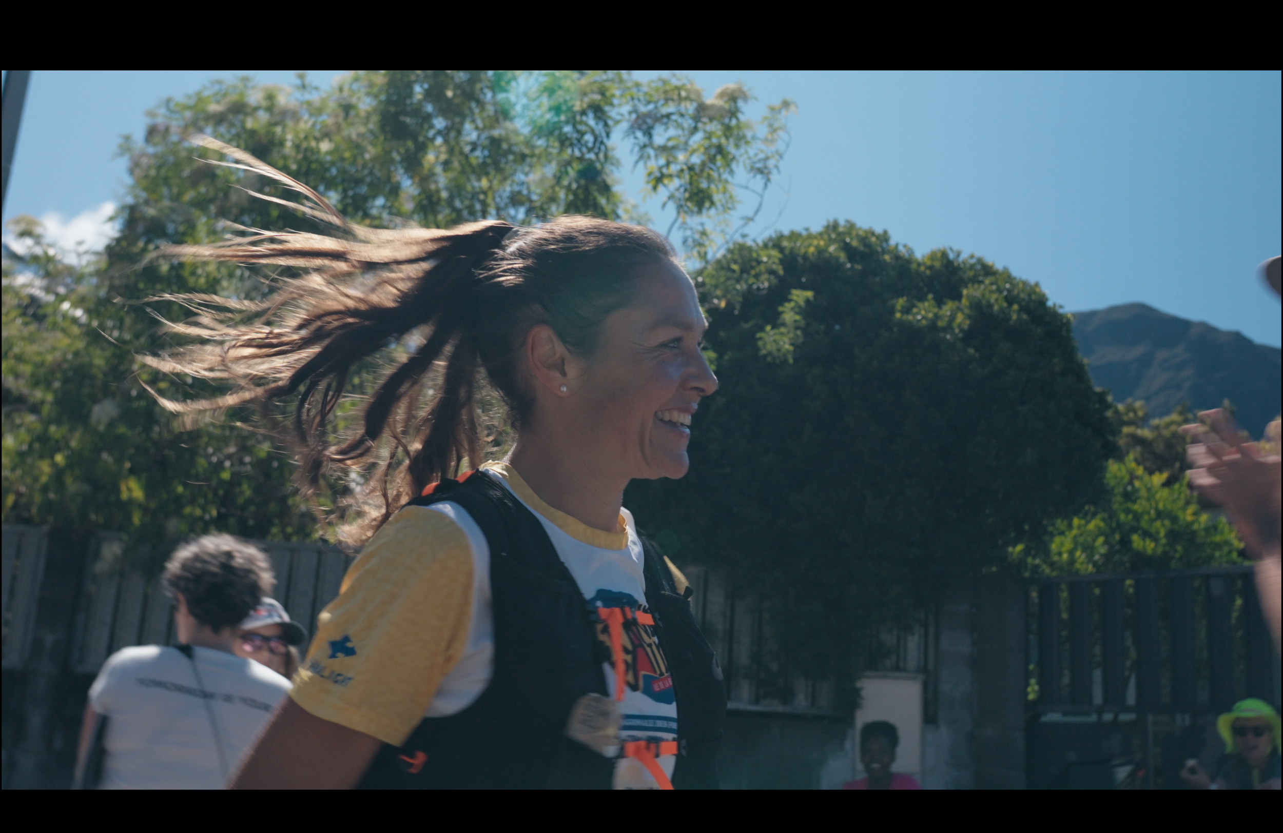 Sylvaine Cussot running during a sunny day wearing Grand Raid t-shirt smiling
