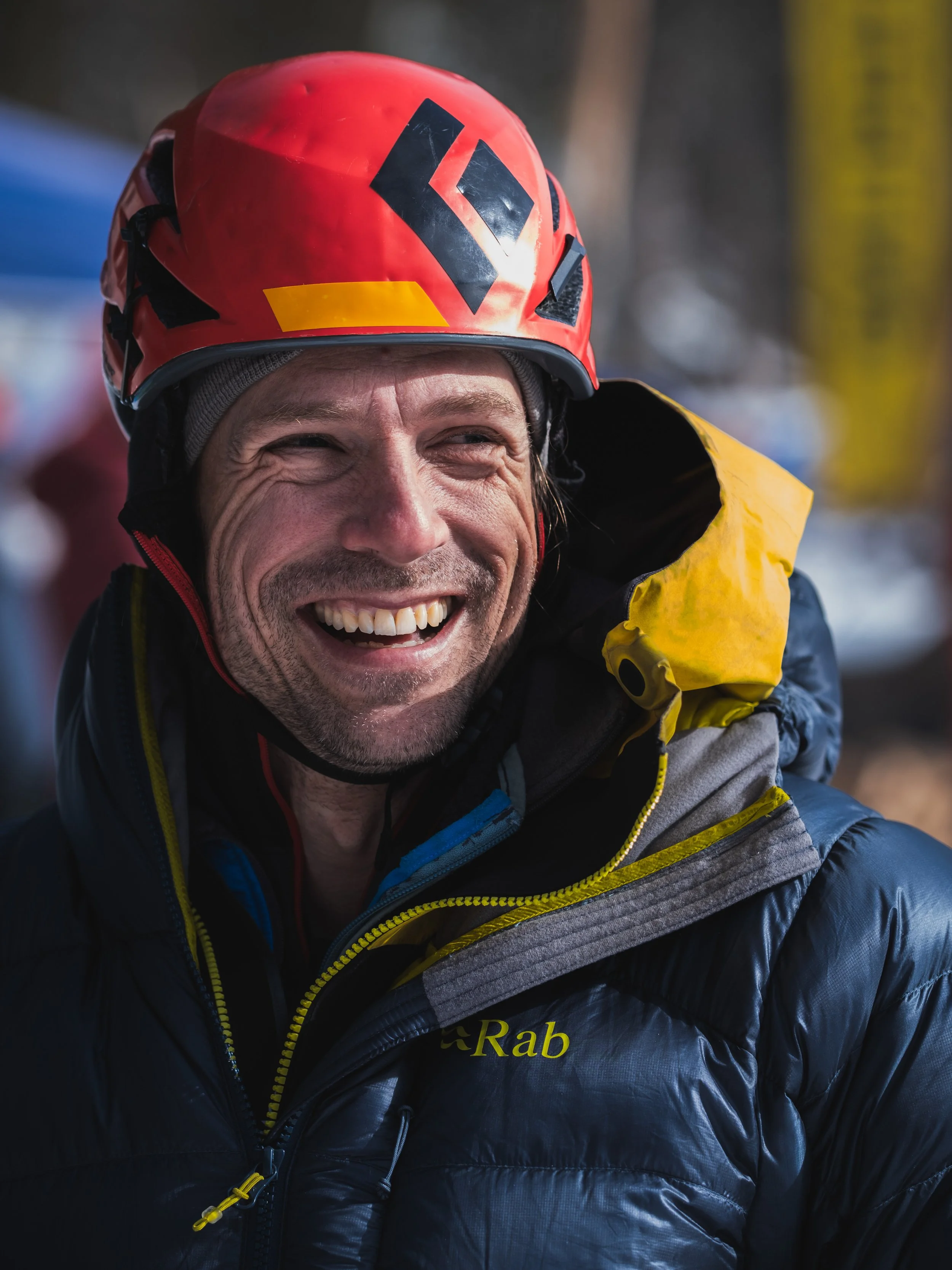 Smiling man wearing climbing helmet and Rab puff jacket