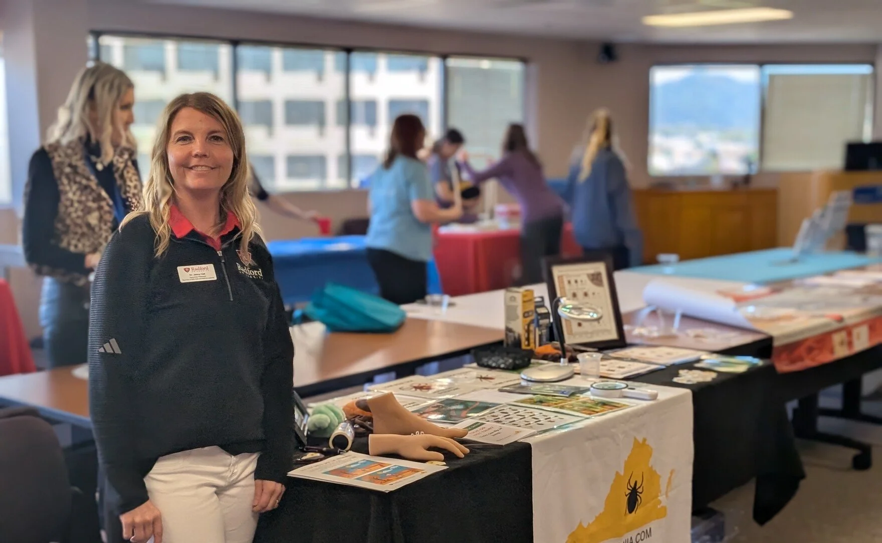 Public health expert Jenny Hall stands in front of her table for her outreach project Ticks in Virginia at a public health fair