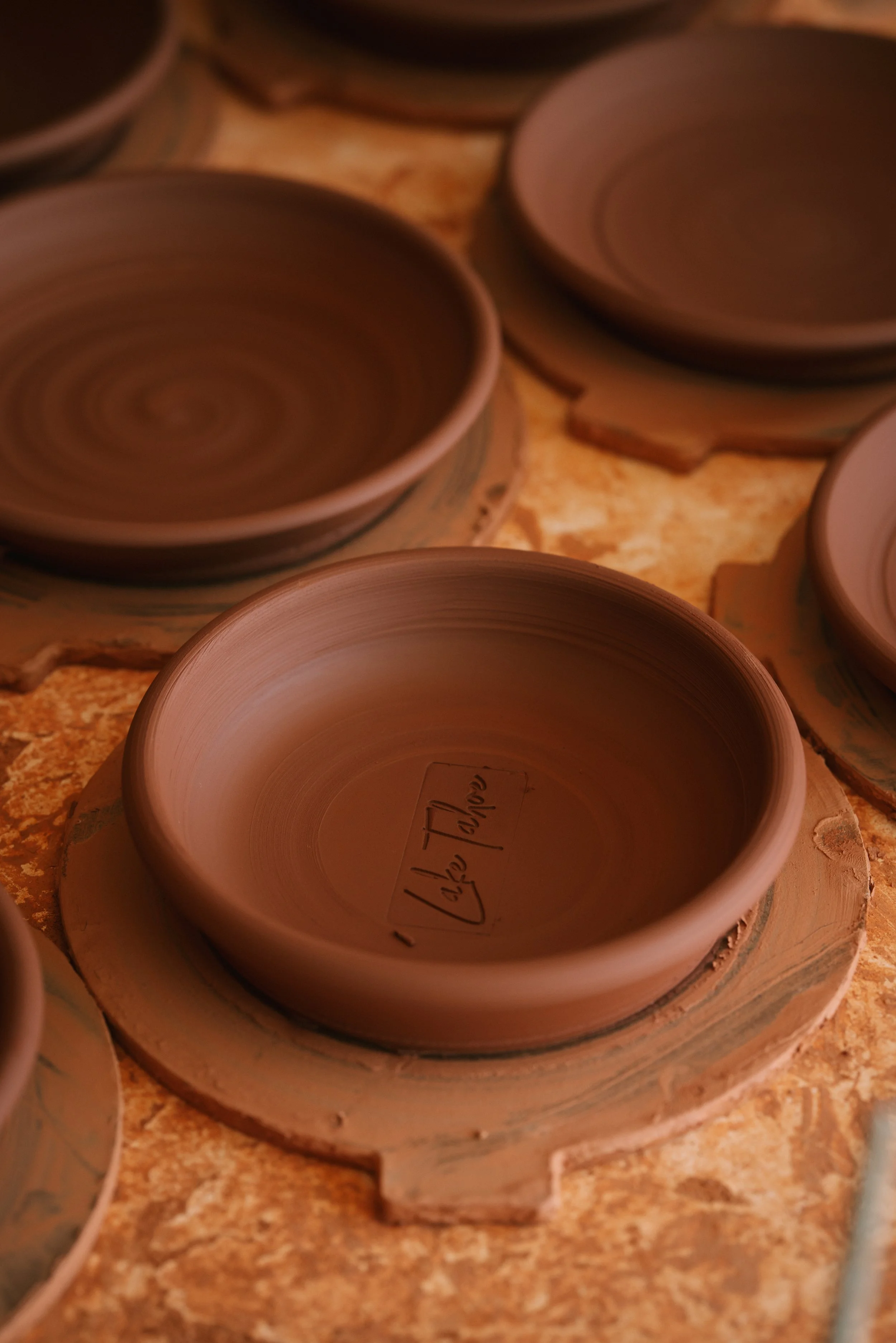 Unfinished clay pottery bowls on a worktable, with one bowl labeled