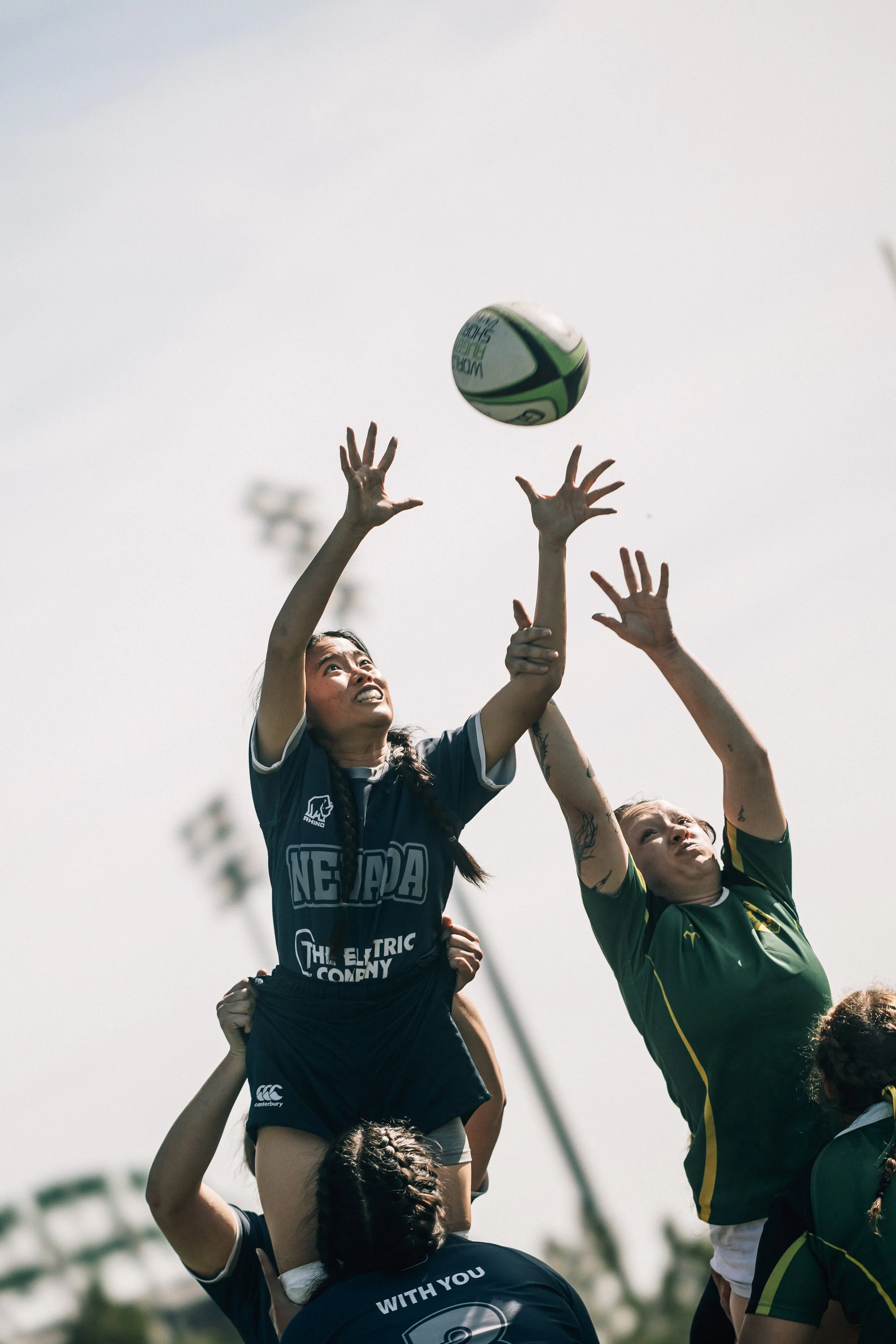 A women's rugby match where players are jumping to catch the ball during a line-out.