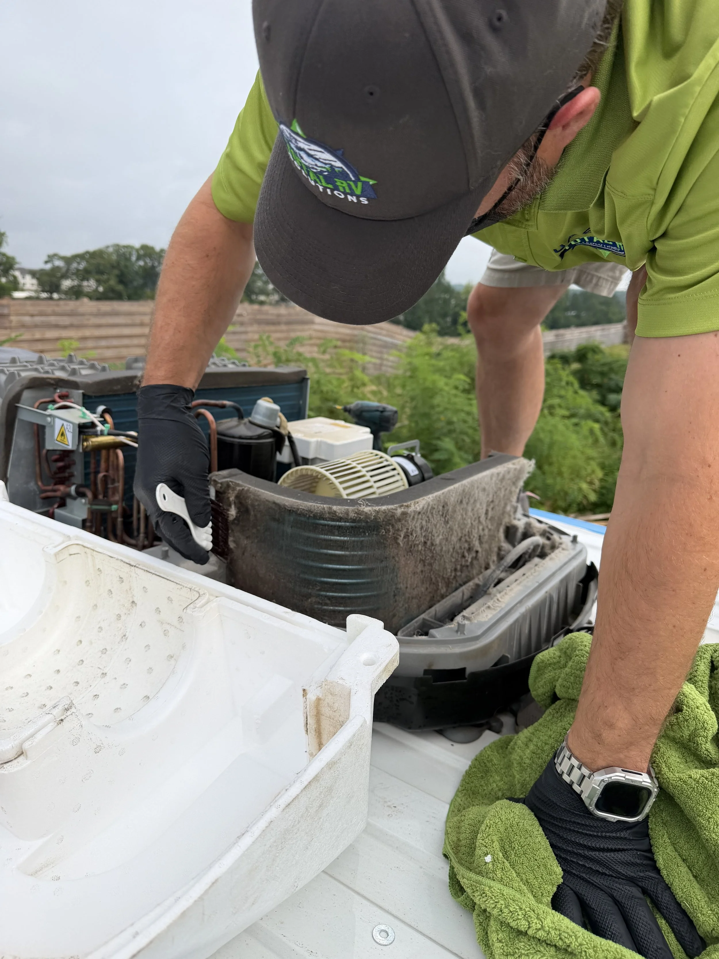 Debris being removed from an RV rooftop air conditioner coil