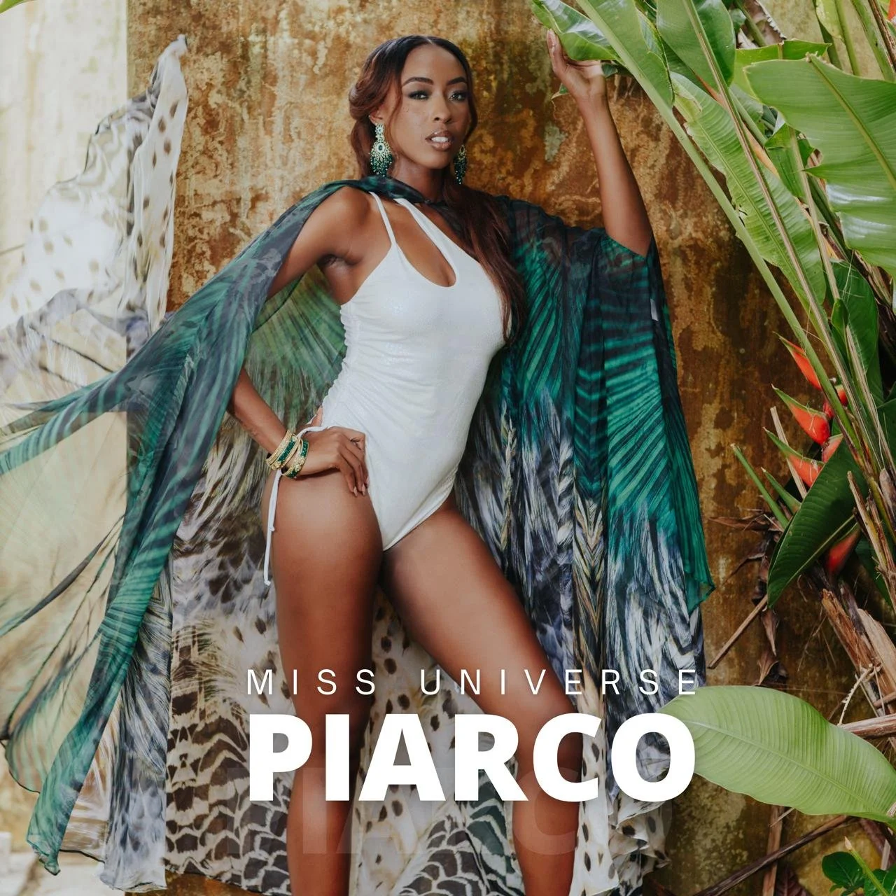 Miss Universe Piaro posing in a tropical setting with green plants and foliage, wearing a white swimsuit, turquoise earrings, and colorful bracelets.
