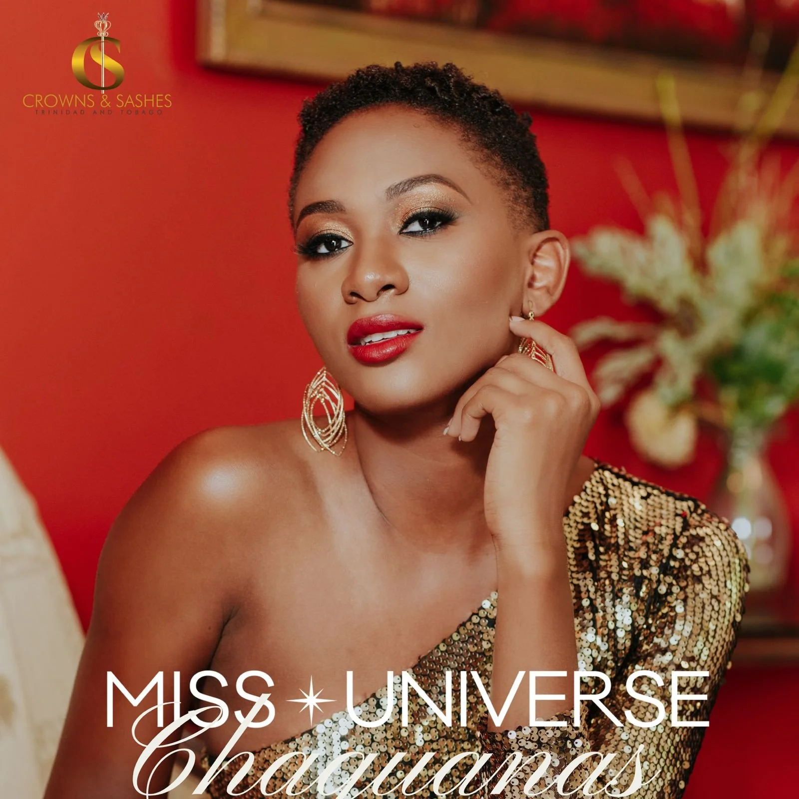 A woman with short curly hair, wearing gold and black sequined top and gold earrings, posing against a red background with flowers in a vase. Text on the image reads "Miss Universe Chauharas" and the logo of Crowns & Sashes.