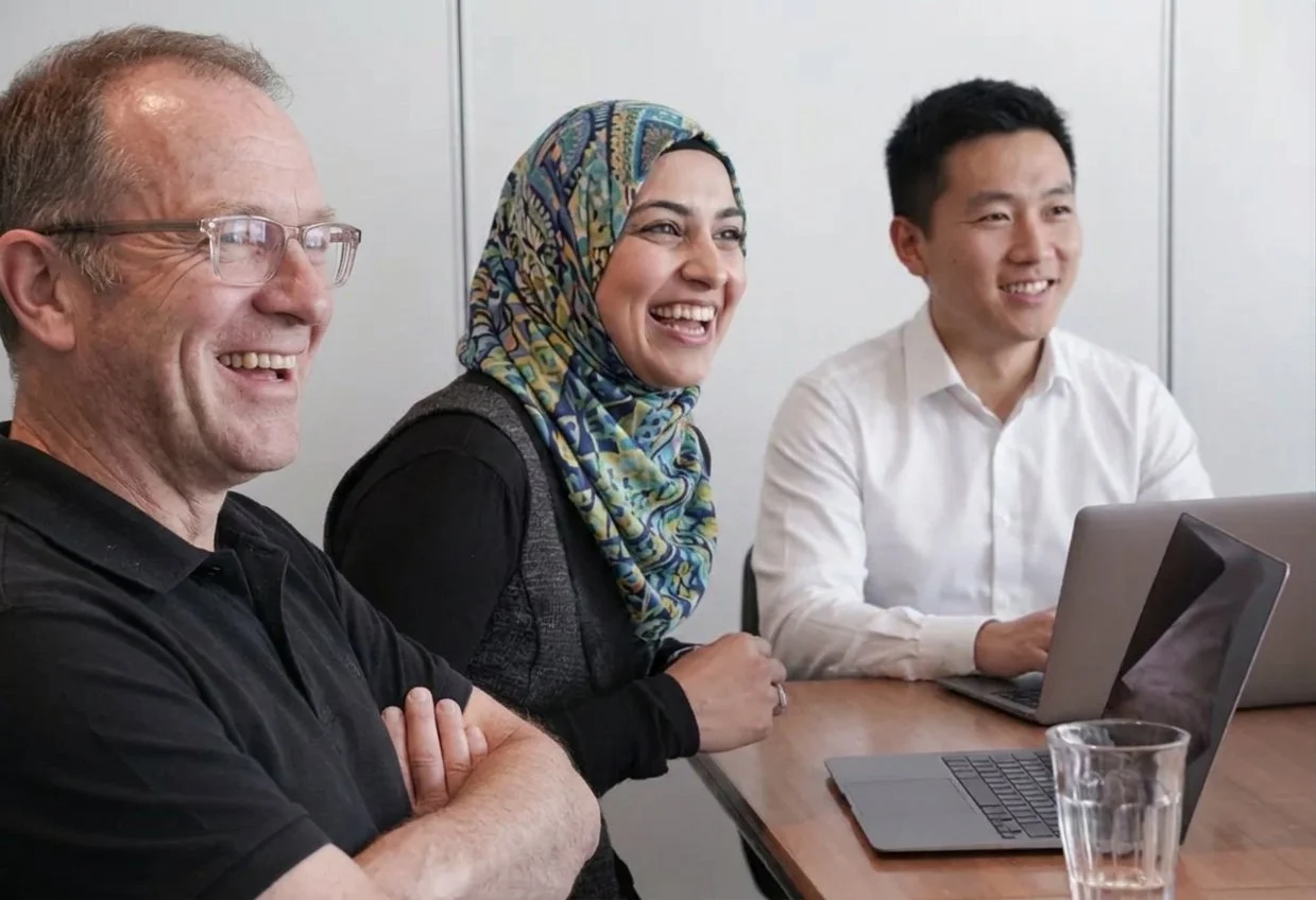 Smiling woman in conversation with colleagues around a meeting table