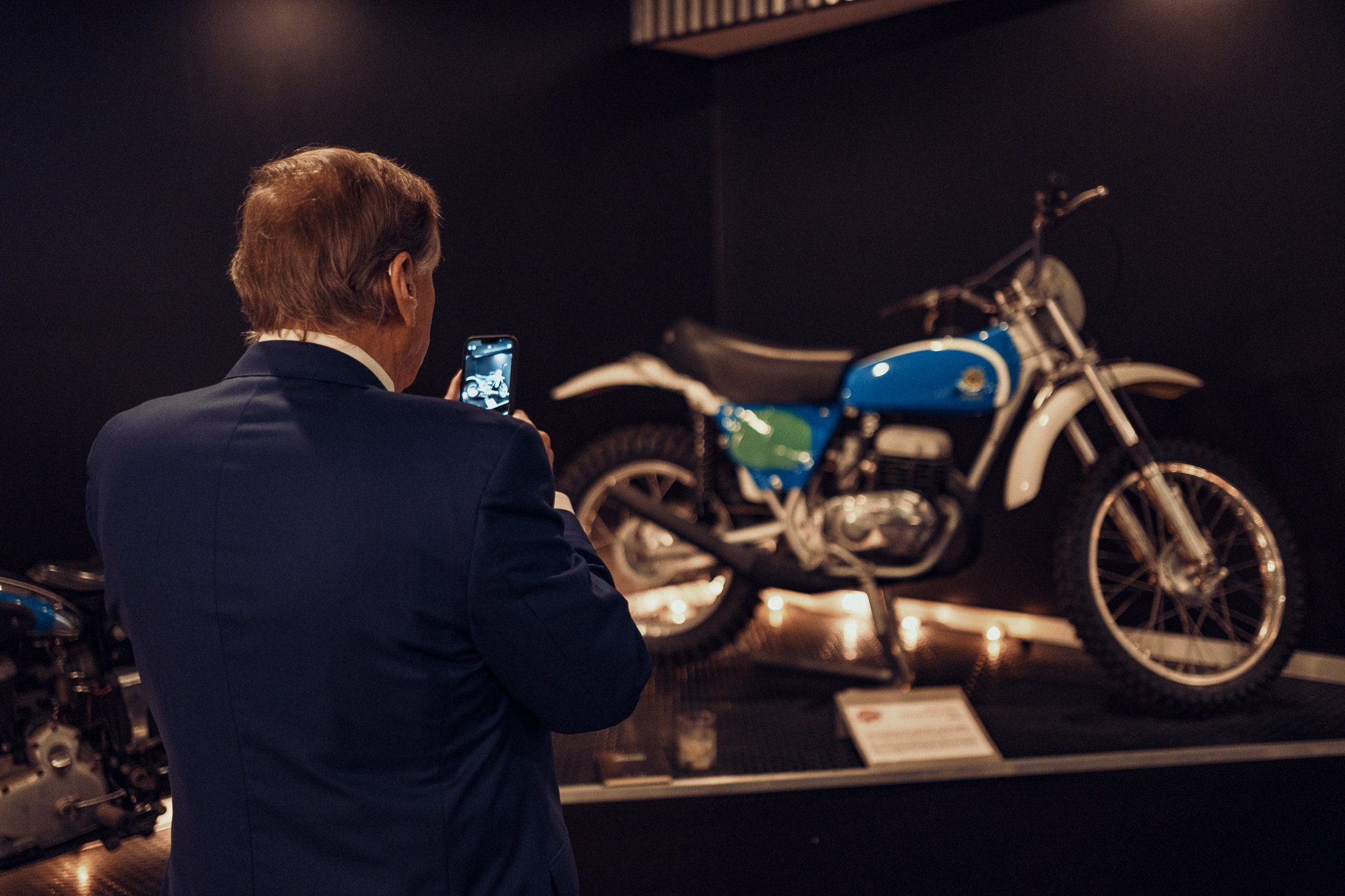 business man taking photo of vintage motorcycle display with his phone at the moto museum event venue st. louis