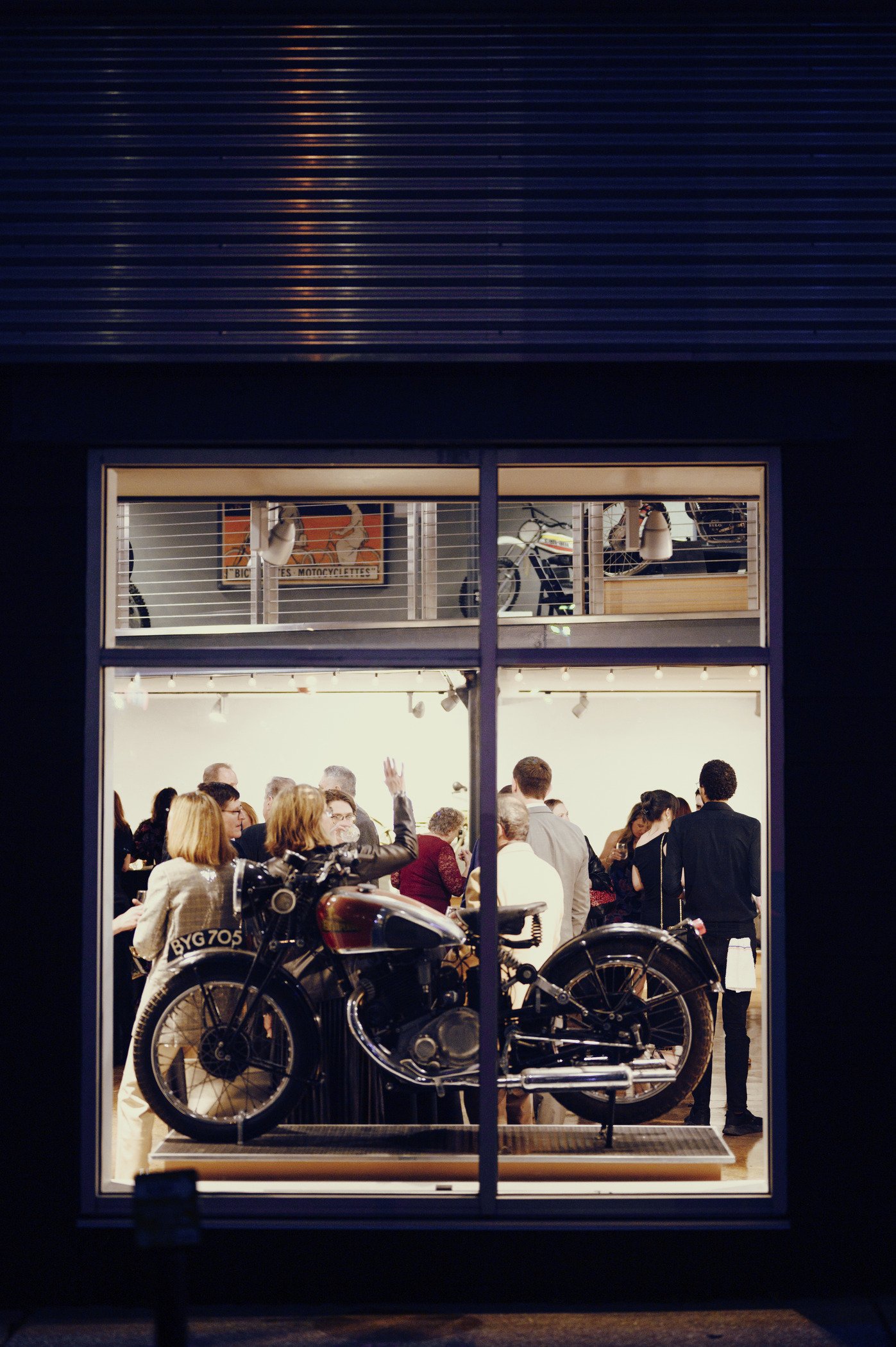outside view through window shows guests inside moto museum event venue at night in st. louis