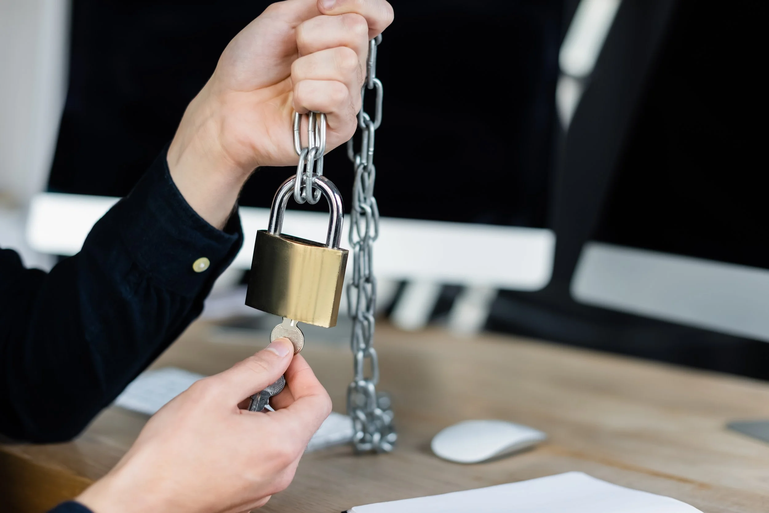 Close-up of a person unlocking a padlock with a key, symbolizing safety, empowerment, and breaking through barriers—core themes of HR Confidential’s mission.