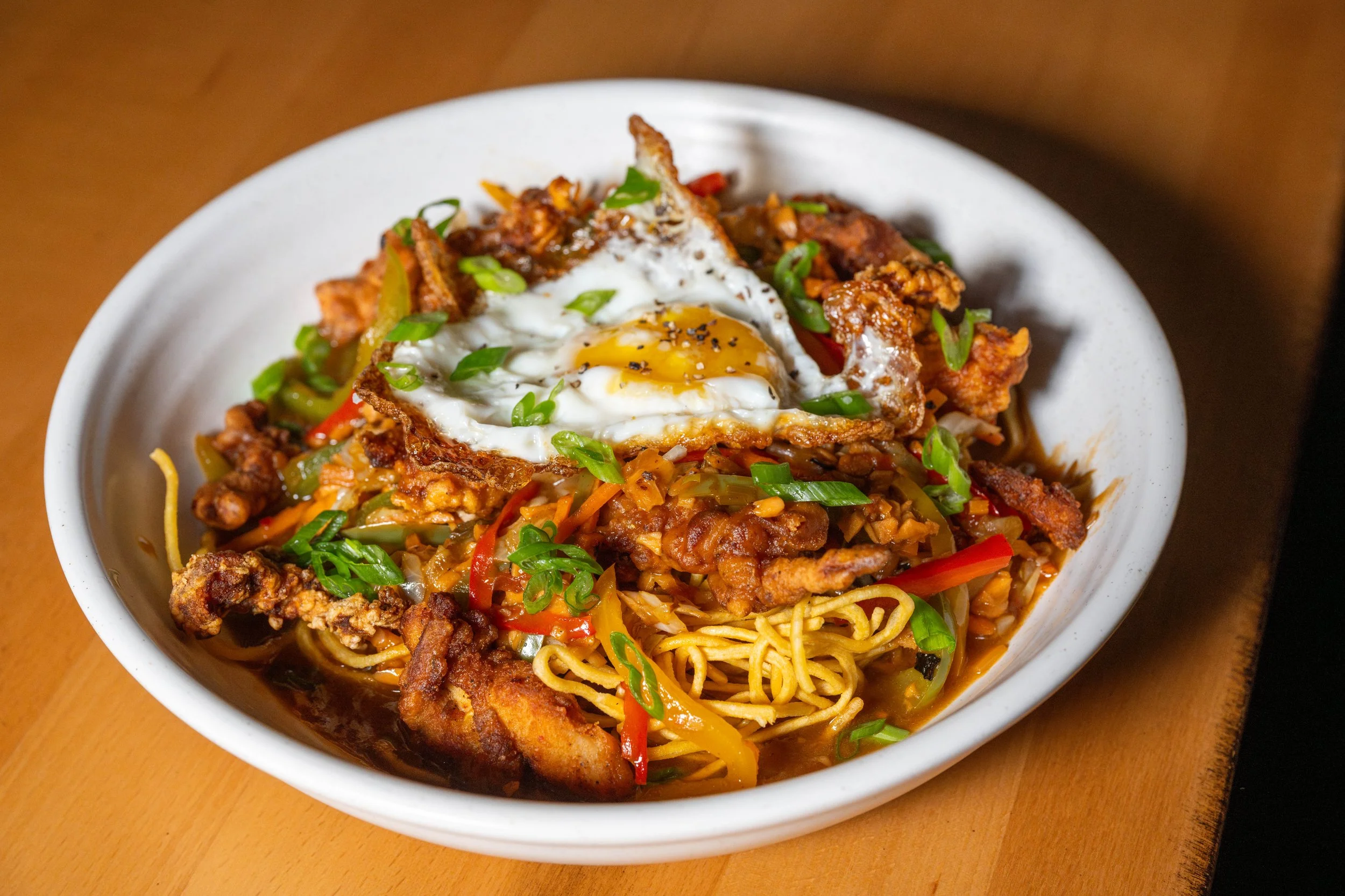 Traditional Indo-Chinese American Chopsuey with crispy noodles, tangy tomato-garlic sauce, crispy chicken, and a sunny side up egg.