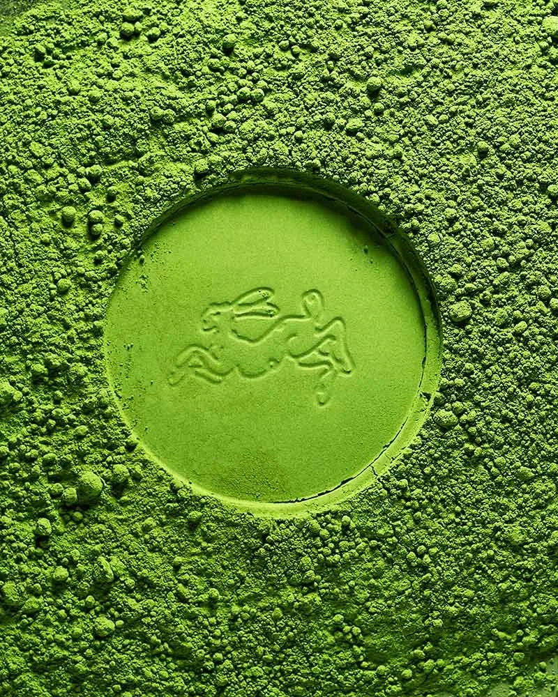Close-up of bright green matcha with a logo of a rabbit in the center, surrounded by textured green powder.