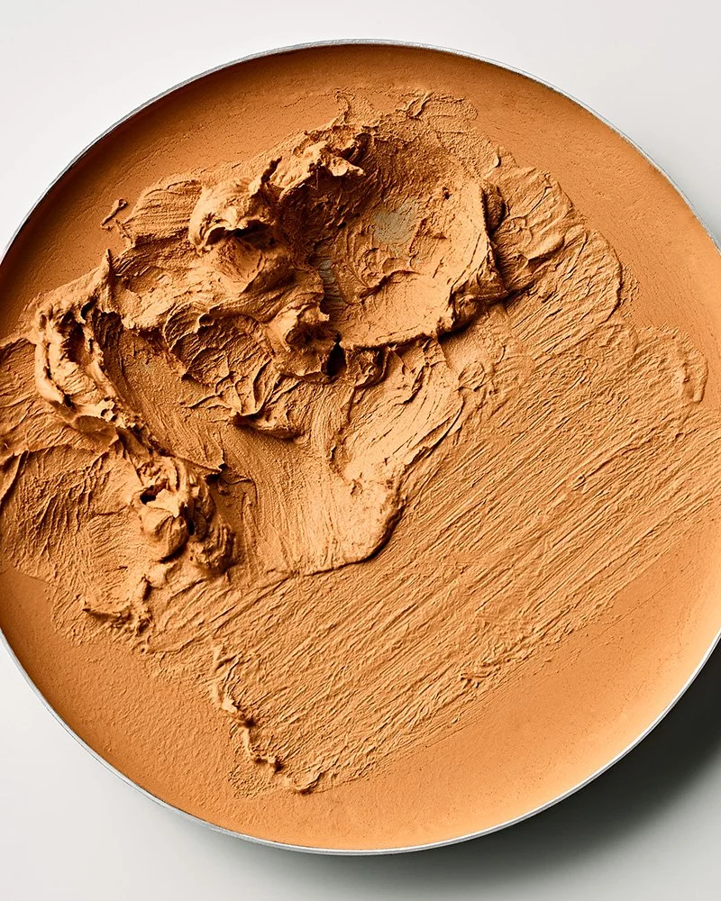 Close-up of light brown pressed powder makeup in a round container.