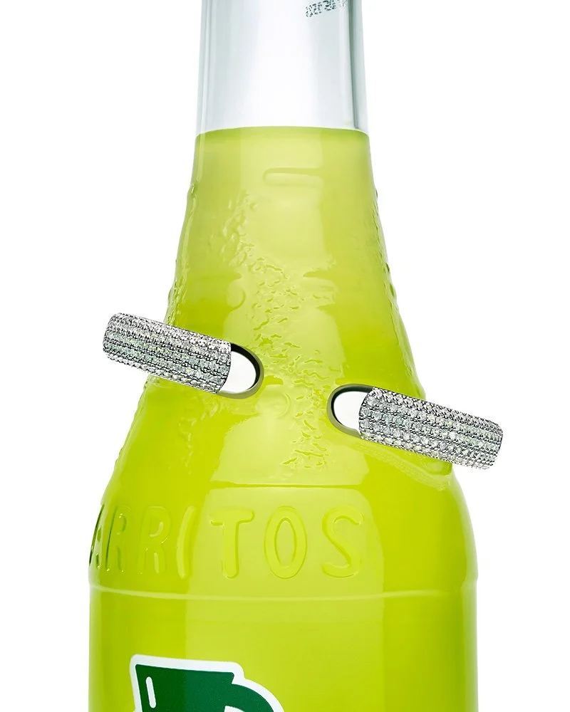 Close-up of a green glass bottle with two diamond-encrusted bracelet around the neck.