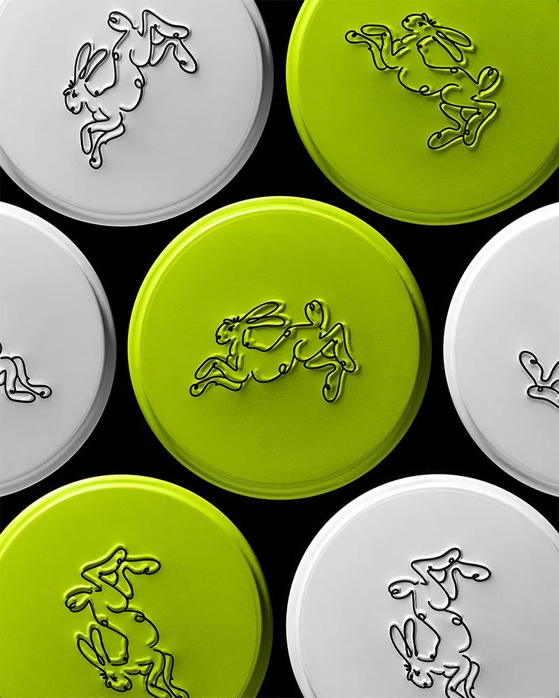 Colorful circular lids, some with black wire illustrations of rabbits and others with chickens, arranged in a pattern.