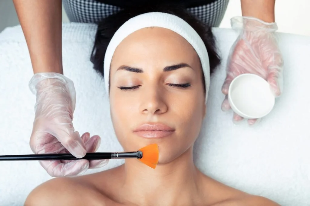 A woman at a spa receiving a Chemical Peel Treatment with gloves facial