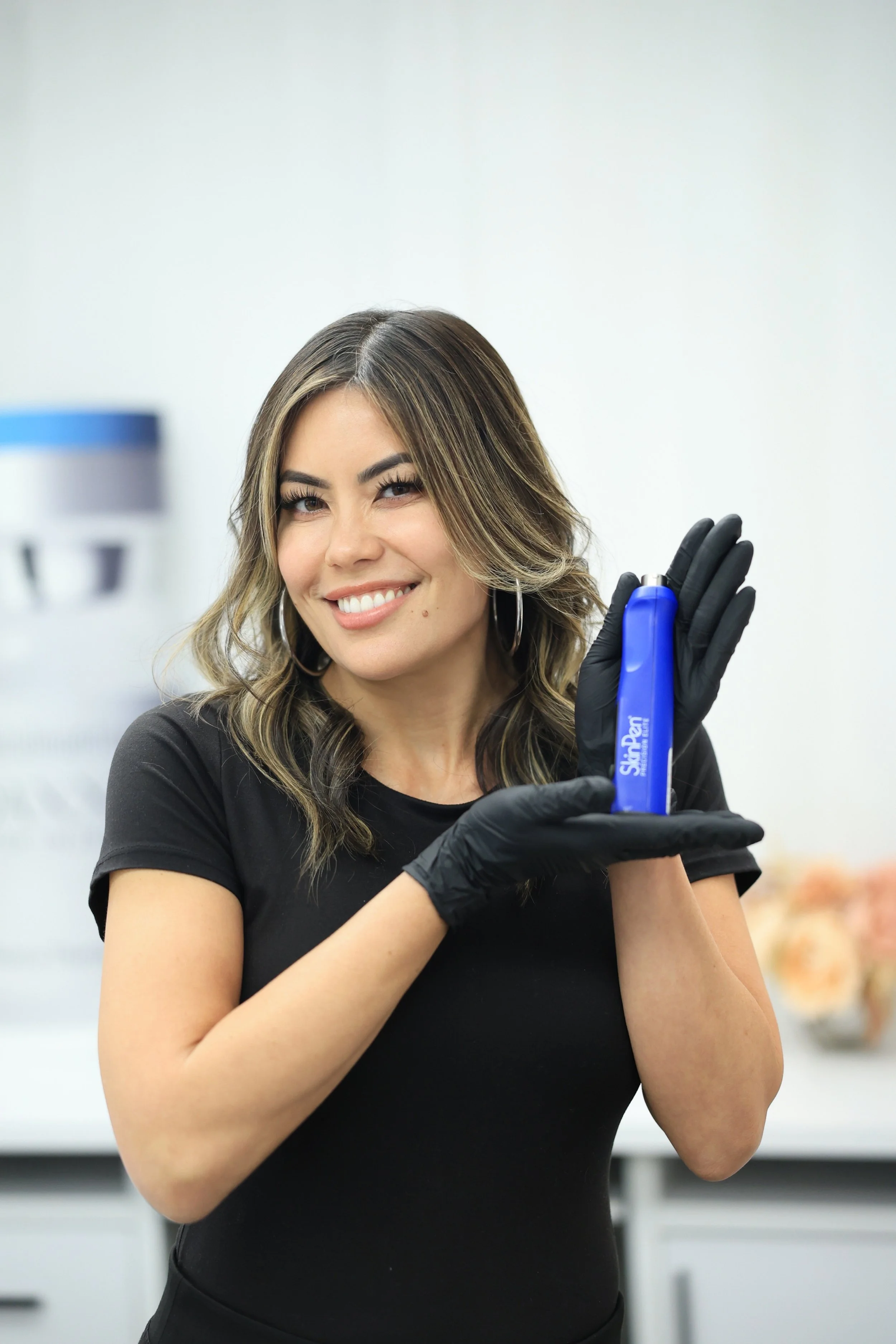 Headshot of a woman smiling while standing in a clinic and holding an item in her hand