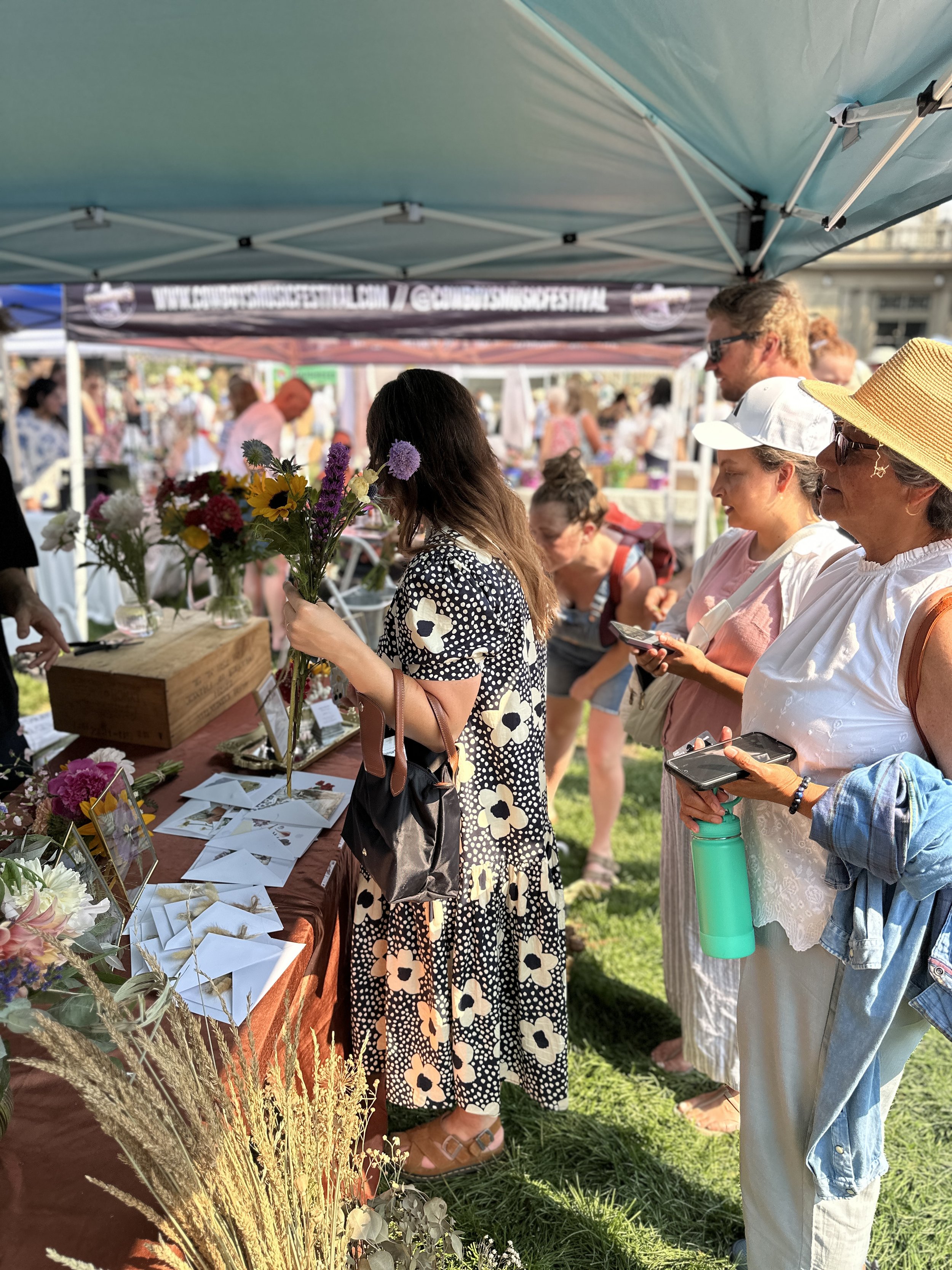 Visitors purchasing flowers from a market booth